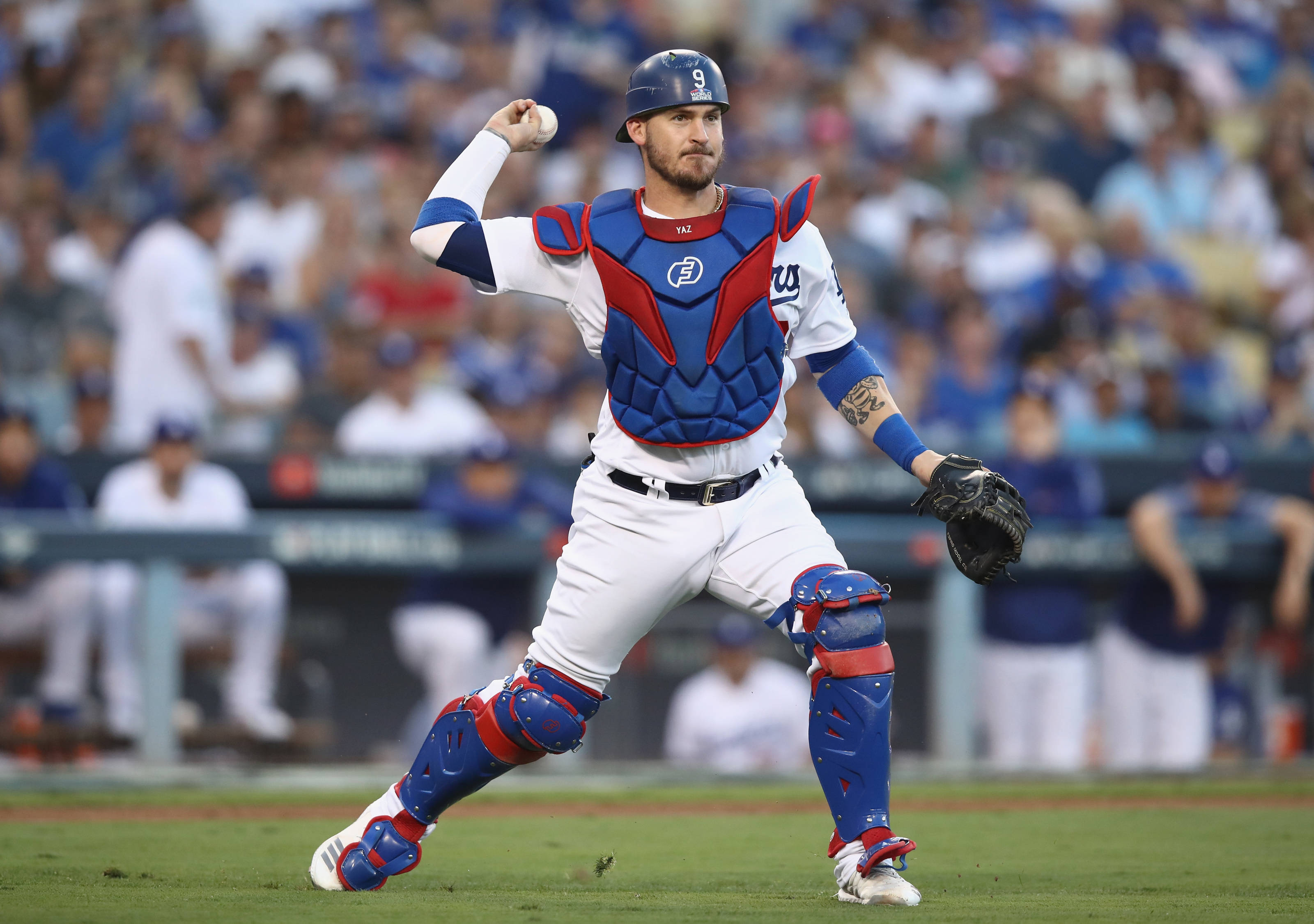 運動 桌布 壁紙 — 一名身穿藍色和紅色裝備的棒球捕手在球場燈光下比賽中準備投球。