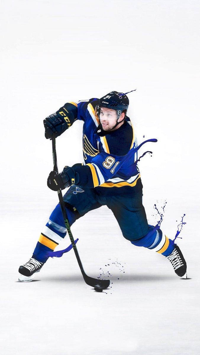 St Louis Blues 桌布 壁紙 — 一名身穿藍色和金色球衣的冰上曲棍球運動員在冰上動態滑行，溜冰鞋周圍有油漆飛濺效果。
