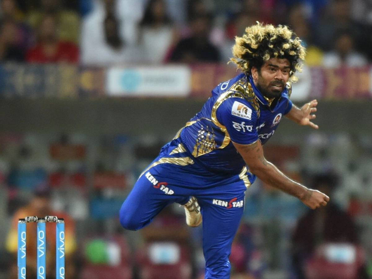 Mumbai Indians 桌布 壁紙 — 一名身穿藍色和金色球衣的板球投手正在動作中，以凌亂的頭髮和強烈的專注力投球。