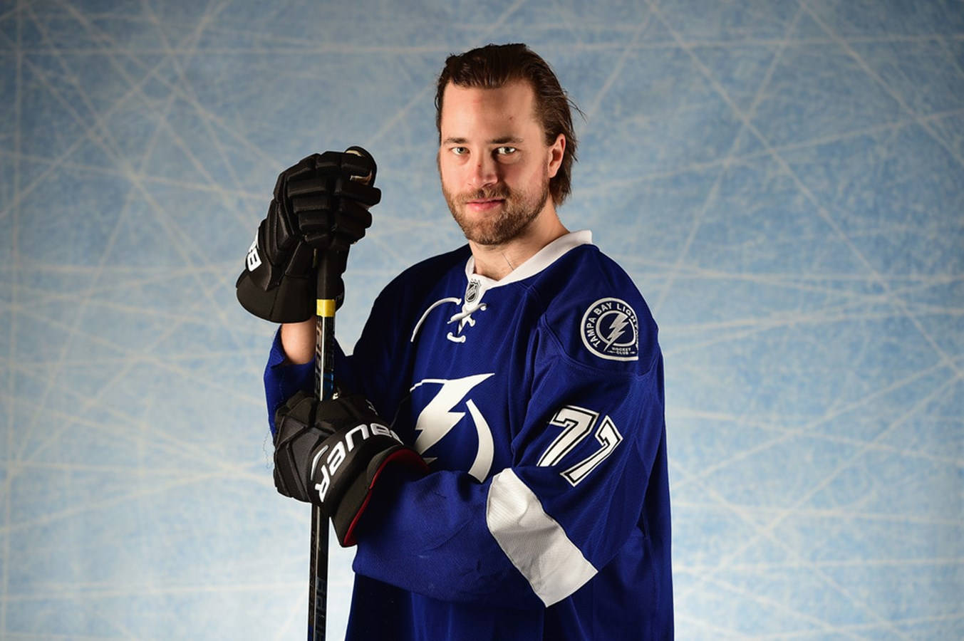 hockey 桌布 壁紙 — 一名身穿藍色坦帕灣閃電隊球衣的冰球運動員，在紋理冰場背景下握著他的球桿。