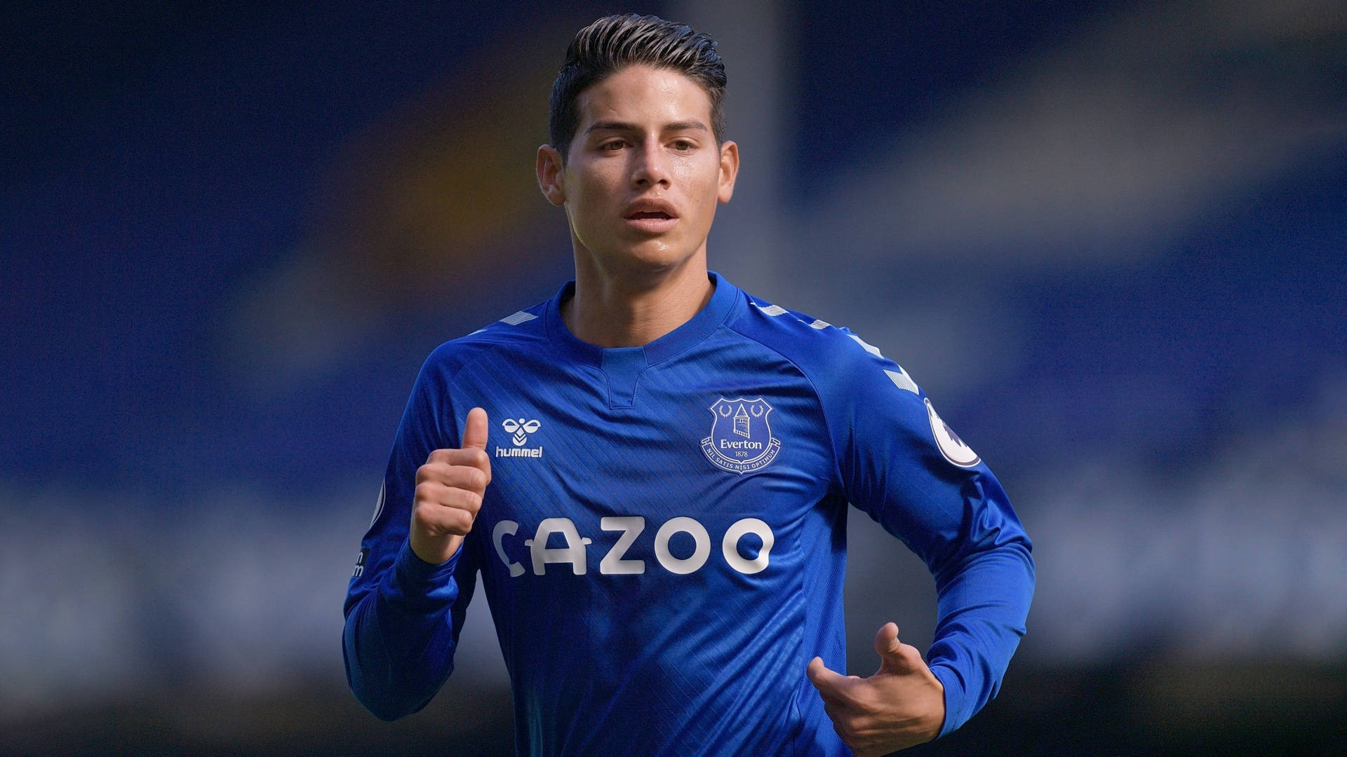 James Rodriguez 桌布 壁紙 — 一名身穿藍色埃弗頓球衣的足球運動員在球場上奔跑時豎起大拇指。