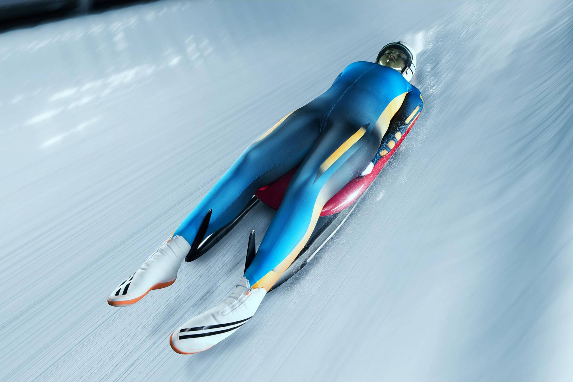 Athletic 桌布 壁紙 — 一名身穿藍色套裝的雪橇運動員在冰道上飛馳，動態模糊傳達出高速感。