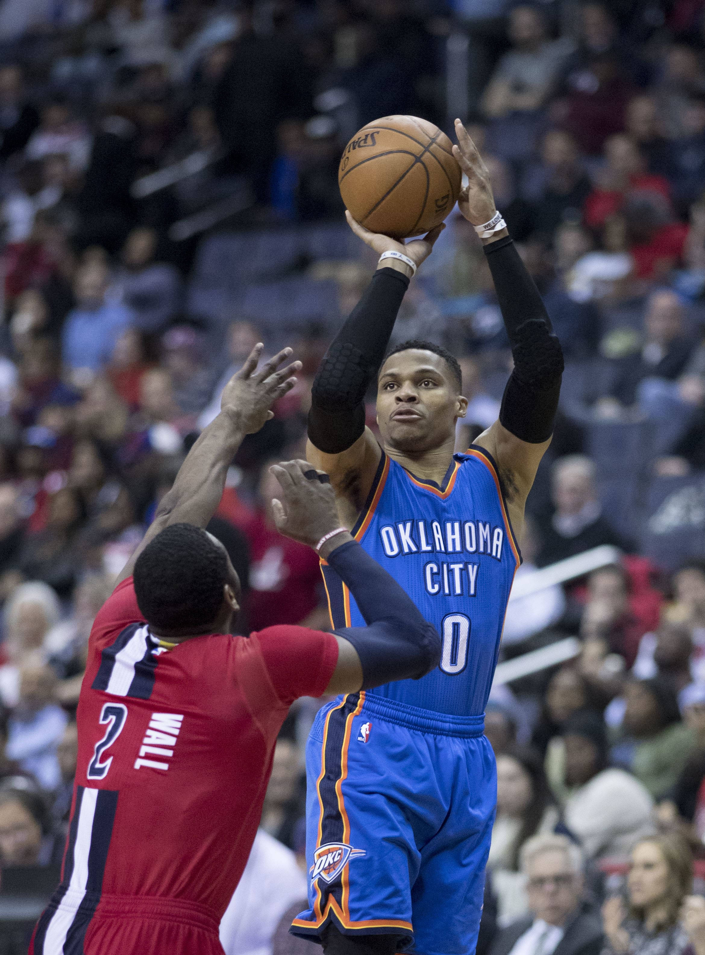 Westbrook 桌布 壁紙 — 一名身穿藍色奧克拉荷馬城球衣的籃球運動員跳投，而一名紅色防守球員試圖封阻。