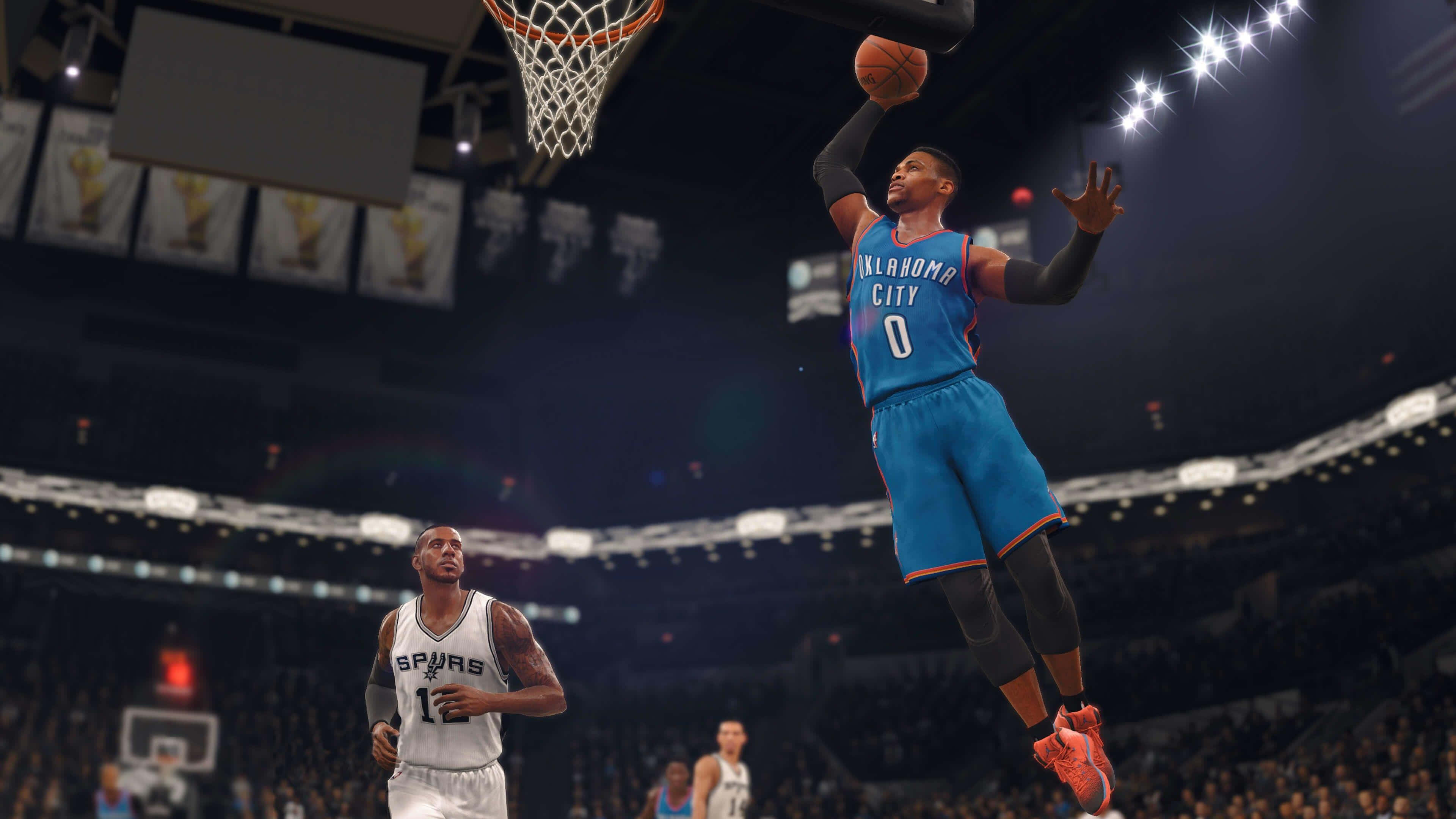 NBA 2k 桌布 壁紙 — 一名身穿藍色奧克拉荷馬城球衣的籃球運動員正在灌籃，而一名馬刺球員在擠滿觀眾的場館下方觀看。