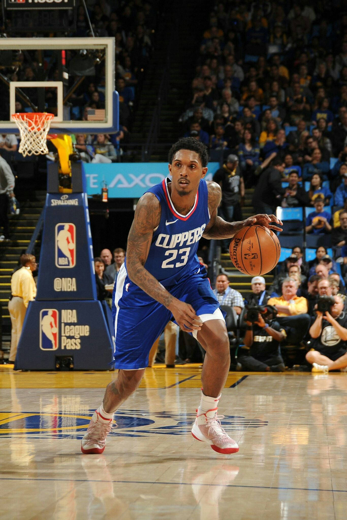 Lou Williams 桌布 壁紙 — 一名身穿藍色快艇隊球衣的籃球運動員在明亮的場館燈光下，於激烈的NBA比賽中運球。
