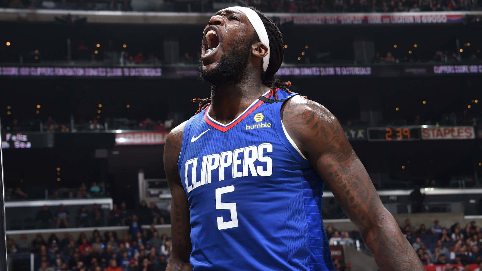 NBA 桌布 壁紙 — 一名身穿藍色快艇隊球衣的籃球運動員在場館燈光下比賽時激情吶喊。