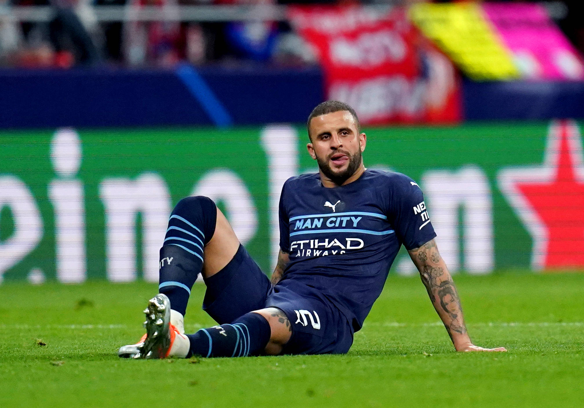 Kyle Walker 桌布 壁紙 — 一名身穿藍色曼城球衣的足球員坐在充滿活力的綠色球場上，因錯失機會而顯得沮喪。