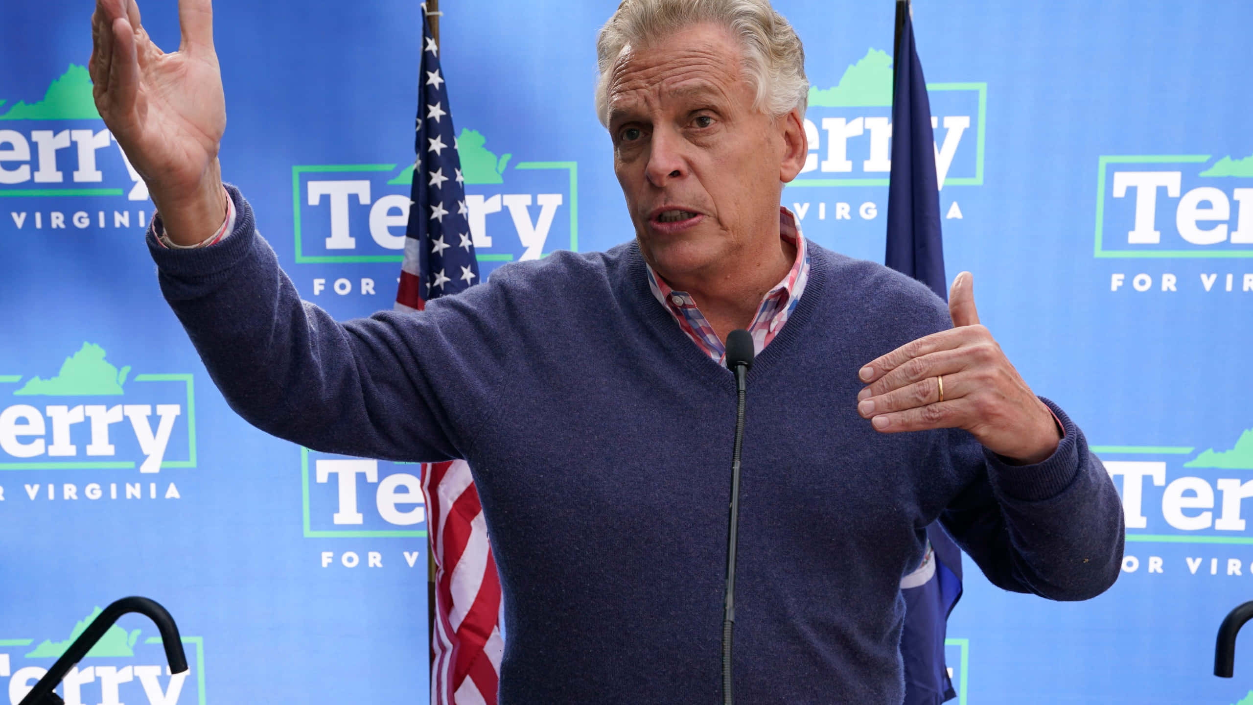 Celebrity 桌布 壁紙 — 一名身穿藍色毛衣的男子在「Terry for Virginia」競選活動中熱情地比劃手勢發言，身後有美國國旗。