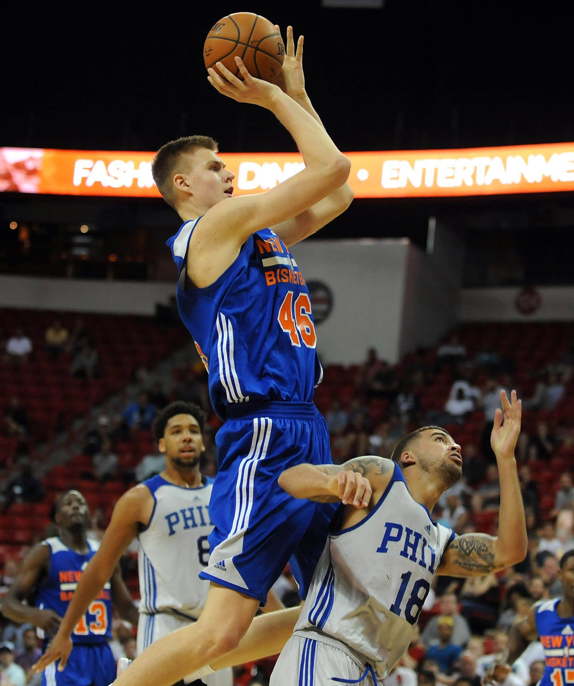 Kristaps Porzingis 桌布 壁紙 — 一名身穿藍色球衣、背號46的籃球運動員跳起投籃，而一名身穿白色球衣、背號18的防守球員跳起封阻。