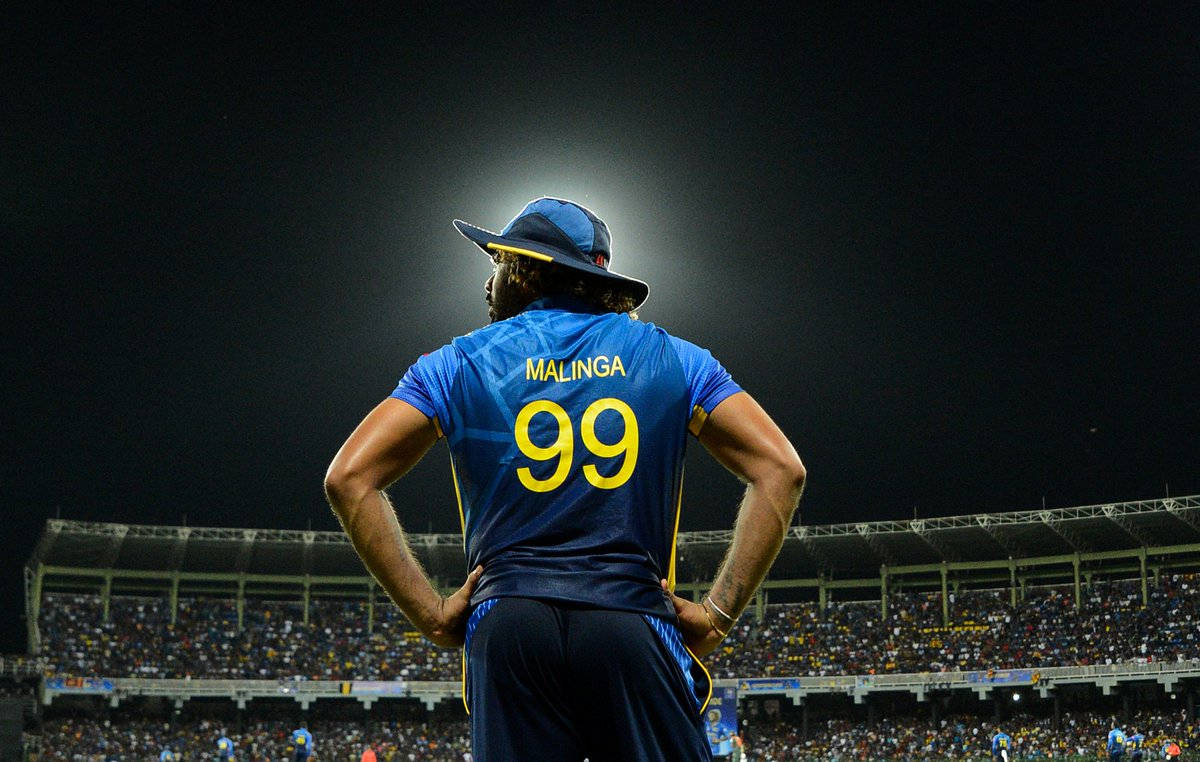 Sri Lanka Cricket 桌布 壁紙 — 一名身穿藍色球衣、號碼99的板球運動員，夜間在球場燈光下雙手叉腰站立。