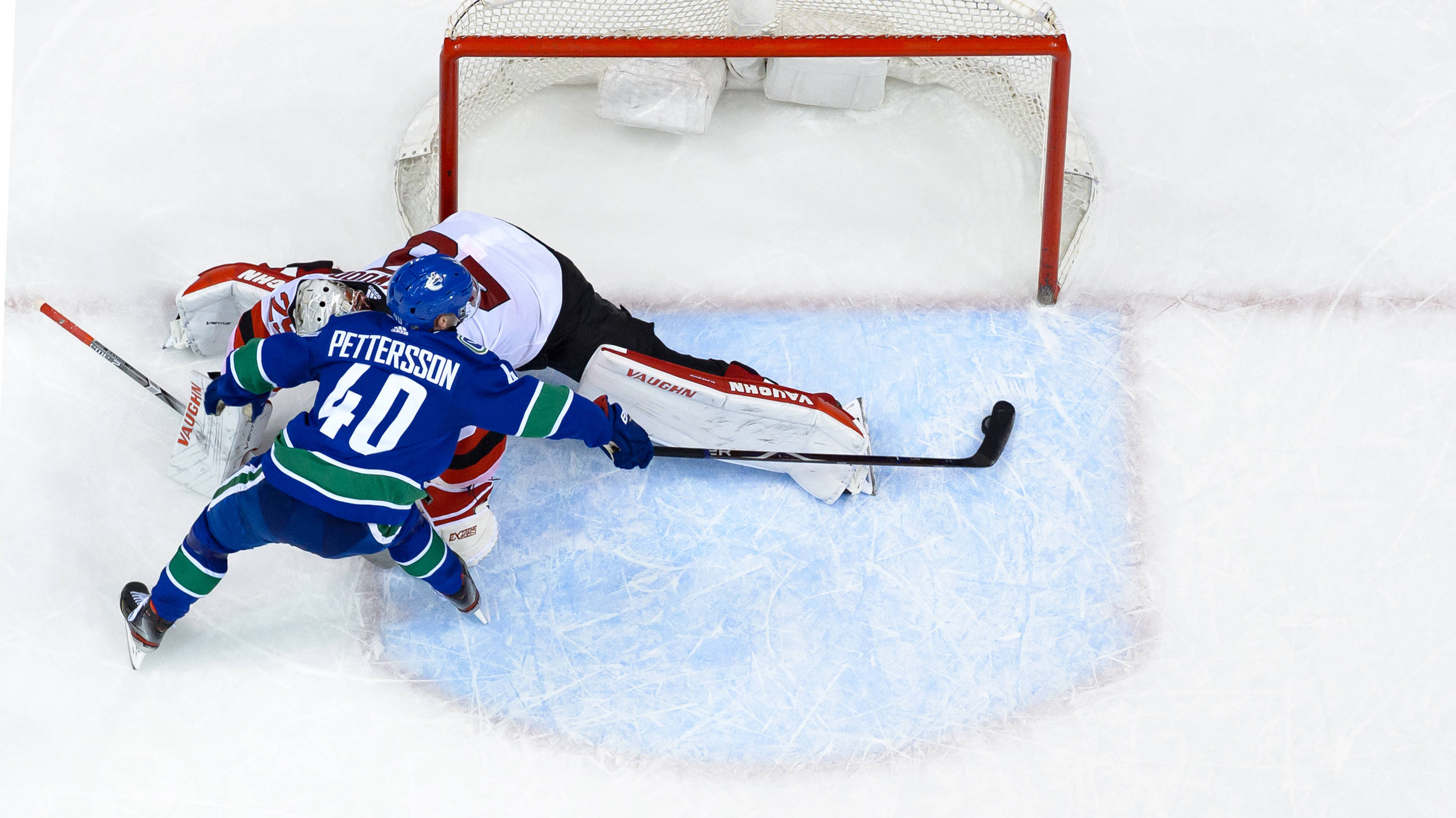 hockey 桌布 壁紙 — 一名身穿藍色球衣40號的冰球運動員在冰上越過一名飛撲的守門員，在紅色框架的球門前得分。
