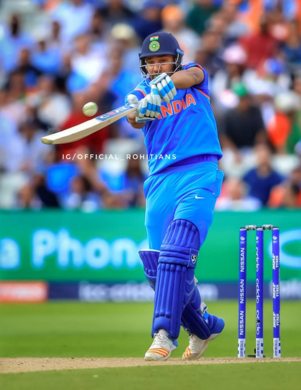 Rohit Sharma 桌布 壁紙 — 一名身穿藍色球衣的印度板球運動員在日間比賽中揮動球棒擊球，背景有觀眾。