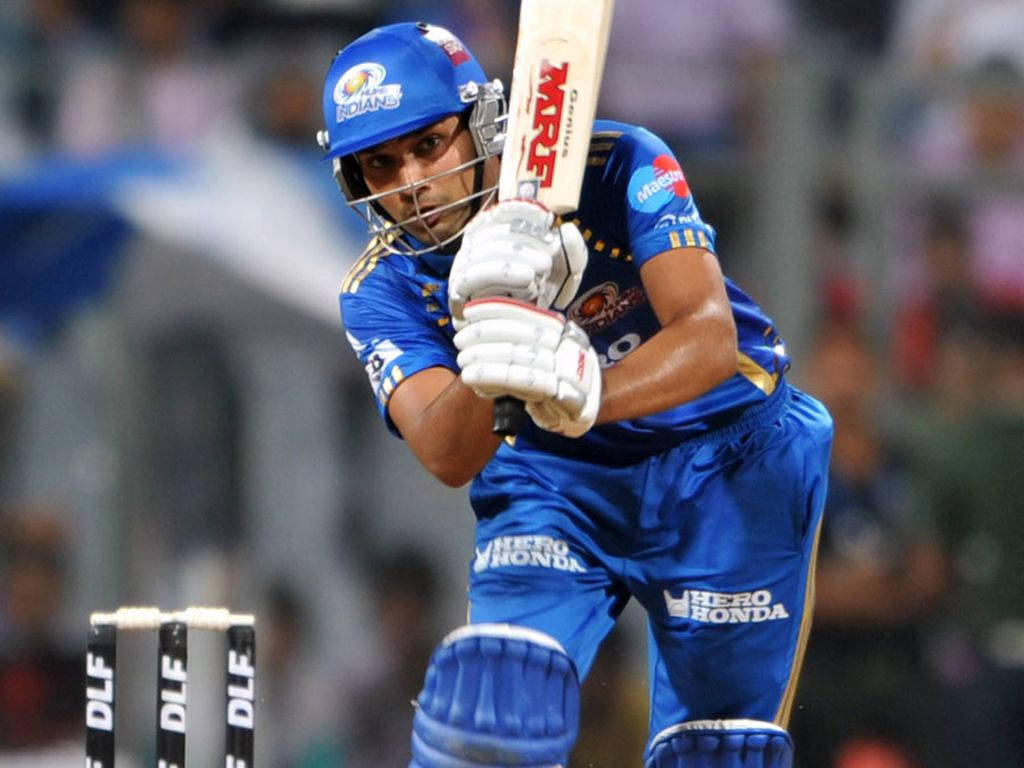 Rohit Sharma 桌布 壁紙 — 一名身穿藍色球衣的板球擊球手在夜間比賽中，在球場燈光下揮動球棒。