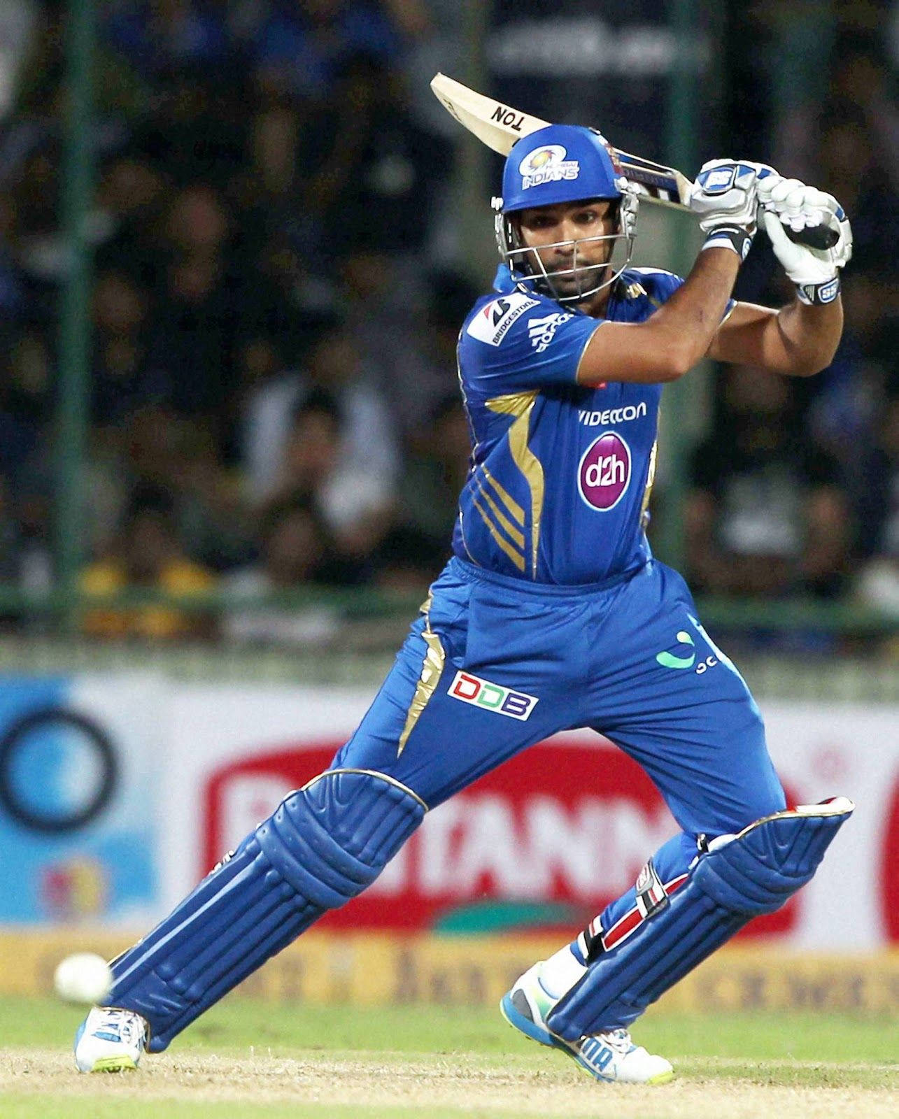 Rohit Sharma 桌布 壁紙 — 一名身穿藍色球衣的板球擊球手在夜間比賽中，在體育場燈光下強力揮動球棒。