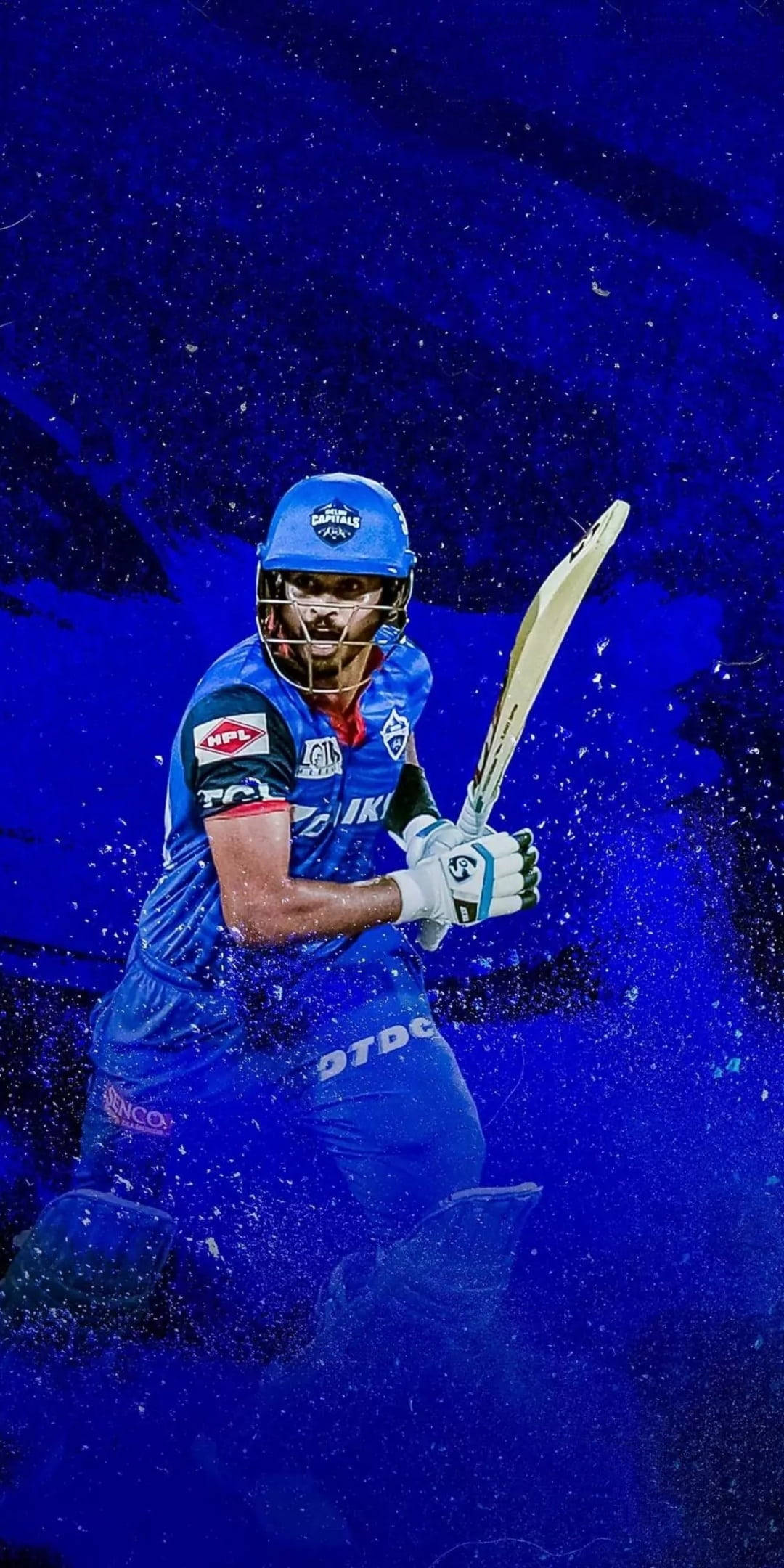Delhi Capitals 桌布 壁紙 — 一名身穿藍色球衣的板球運動員在深色背景中，於動態藍色粒子效果下揮動球棒。