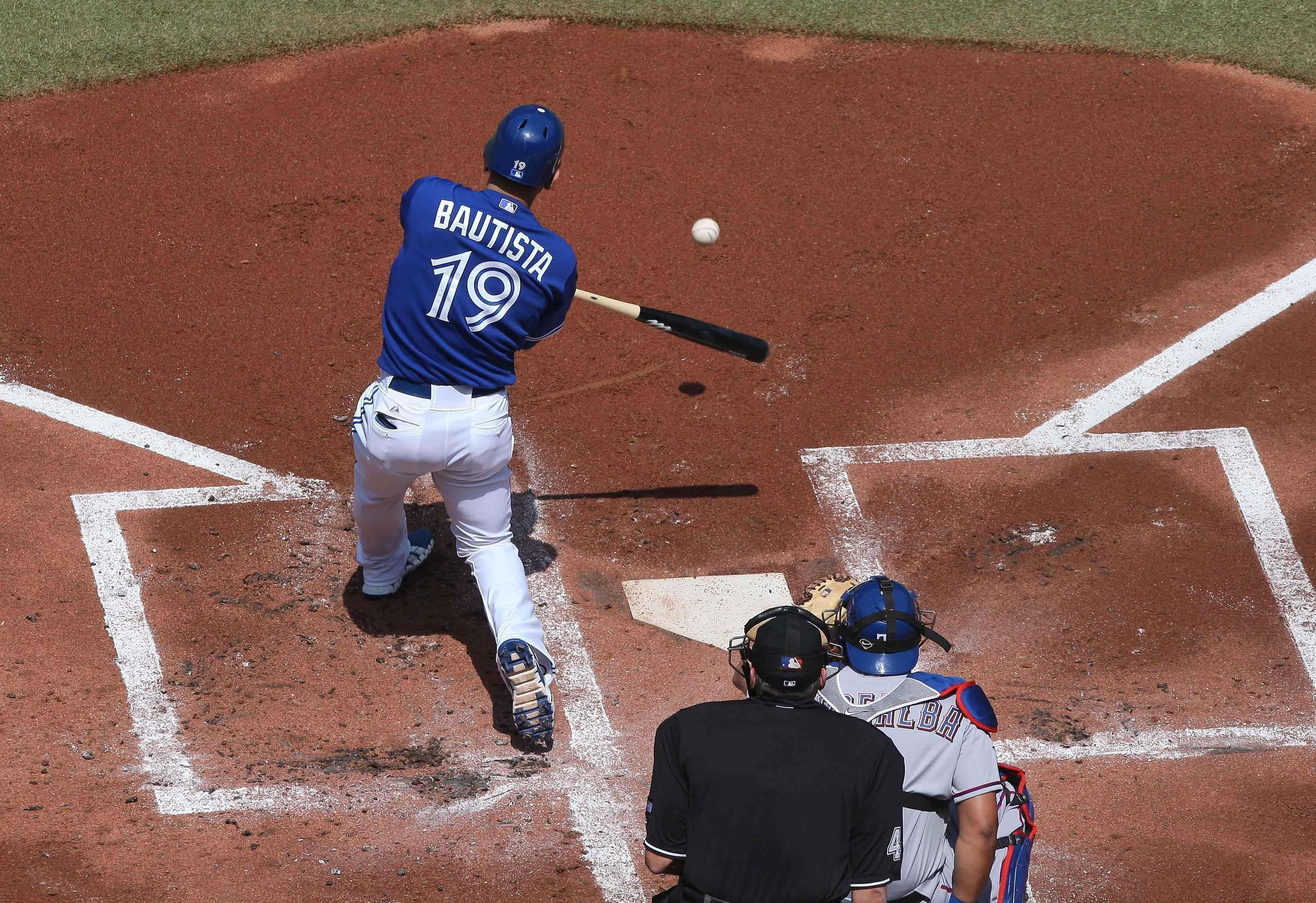 Blue Jays. 桌布 壁紙 — 一名身穿藍色球衣的棒球選手在本壘板附近揮棒擊球，裁判和捕手就位。