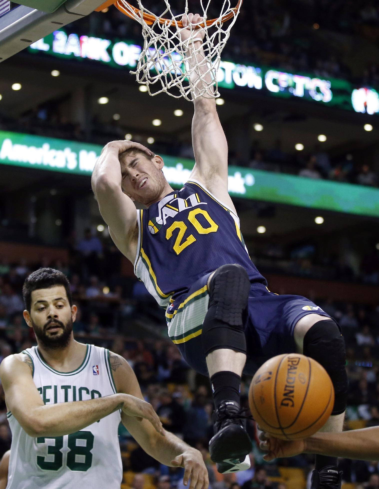 gordon hayward 桌布 壁紙 — 一名身穿藍色球衣的籃球運動員在場館燈光下灌籃，而一名身穿白色球衣的防守球員專注地觀看。