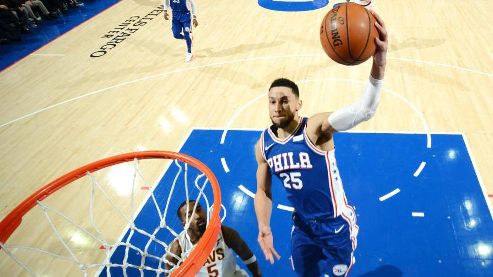 Ben Simmons 桌布 壁紙 — 一名身穿藍色球衣的籃球運動員在激烈的比賽中跳向籃框，球在頭頂上方。