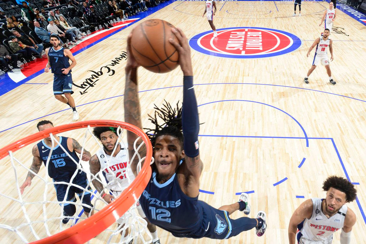 籃球運動員在硬木球場上跳起越過防守球員灌籃。 — Ja Morant 動圖 壁紙