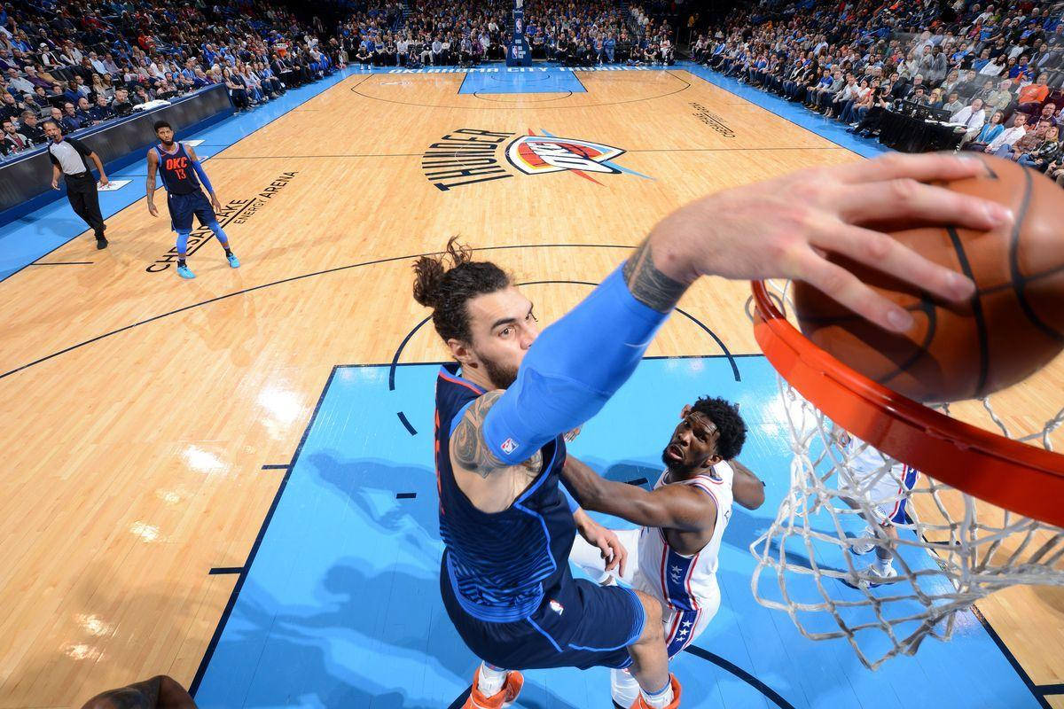 Steven Adams 桌布 壁紙 — 一名身穿藍色球衣的籃球運動員正在灌籃，而一名身穿白色球衣的防守球員試圖封阻投籃。