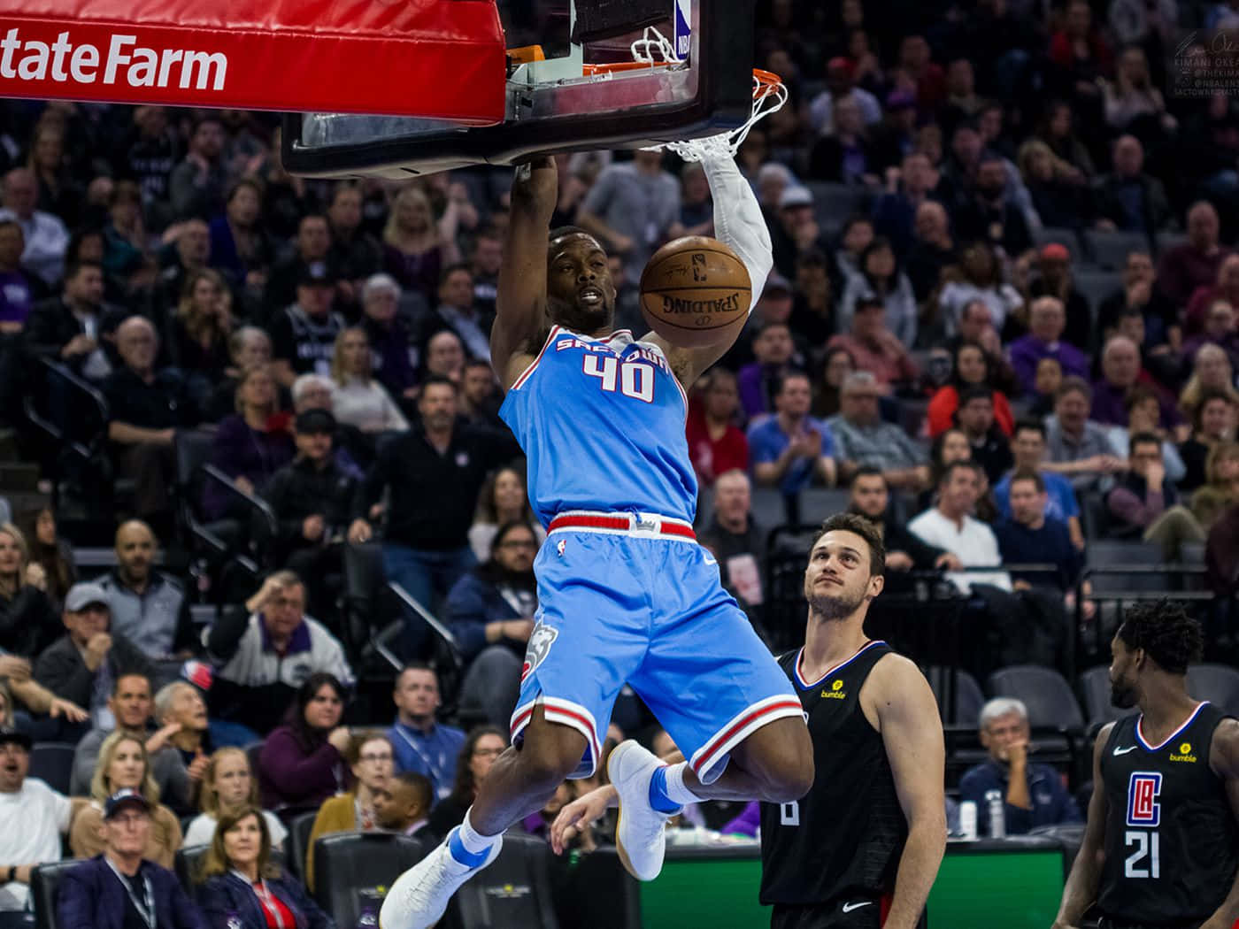 NBA 桌布 壁紙 — 一名身穿藍色球衣的籃球運動員用力扣籃，對手和觀眾都專注地觀看。