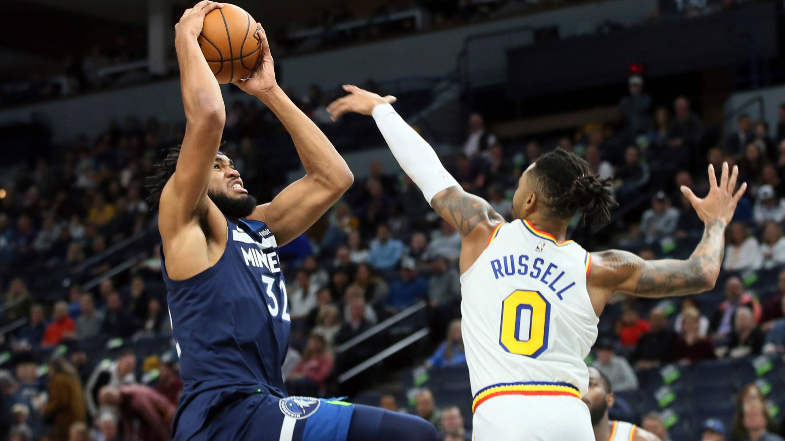 karl-anthony towns 桌布 壁紙 — 一名身穿藍色球衣的籃球運動員跳起投籃，而一名身穿白色球衣的防守球員伸展身體試圖封阻。