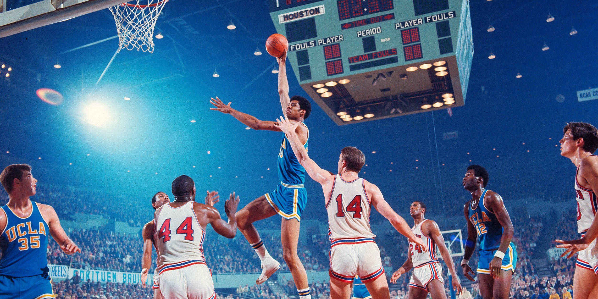 Kareem 桌布 壁紙 — 一名身穿藍色球衣的籃球運動員高高躍起準備灌籃，白色球衣的防守球員在明亮的場館燈光下試圖阻擋他。