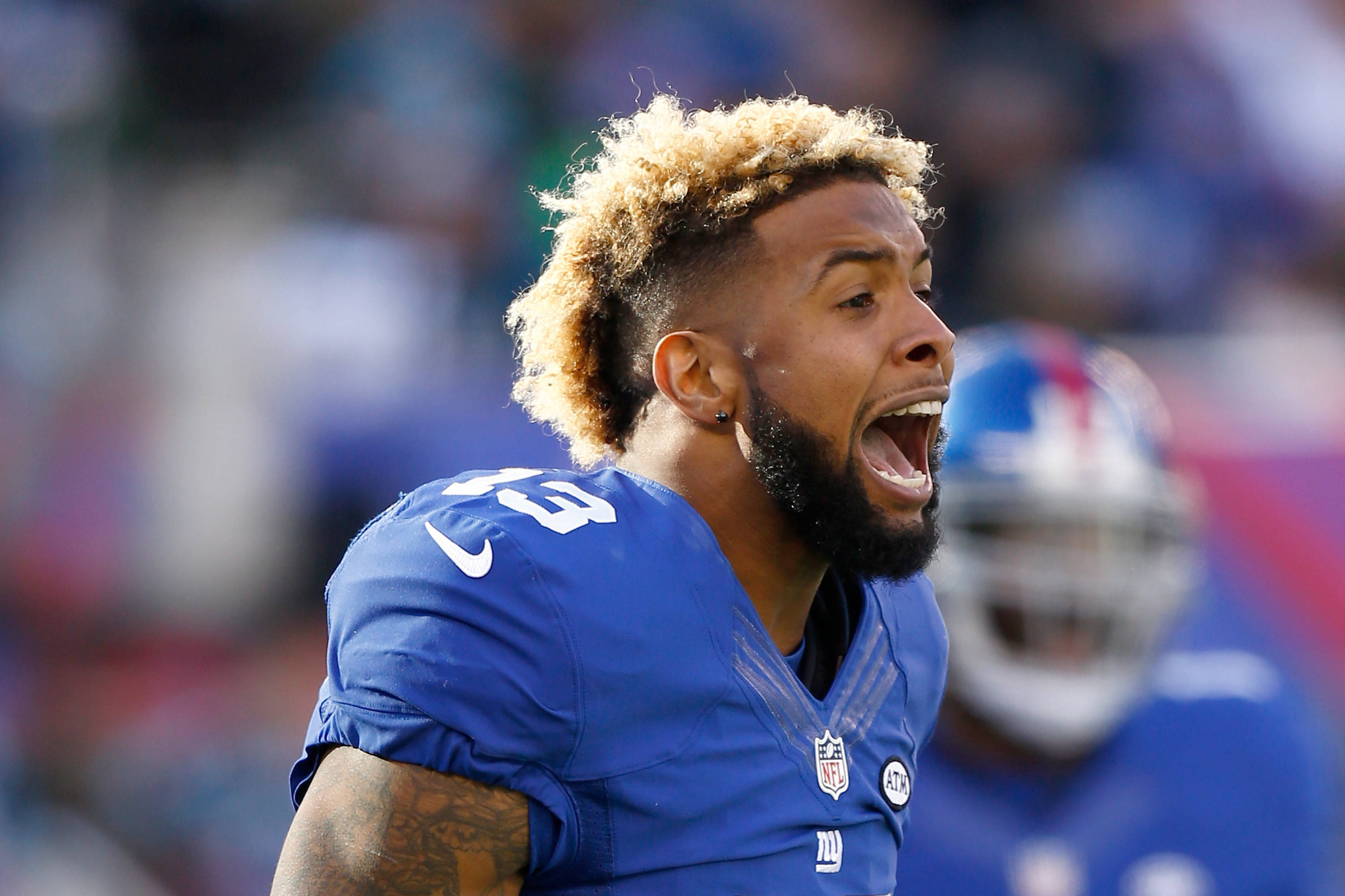 Odell 桌布 壁紙 — 一名身穿藍色球衣的足球運動員在日間比賽中激情吶喊，背景是模糊的體育場。