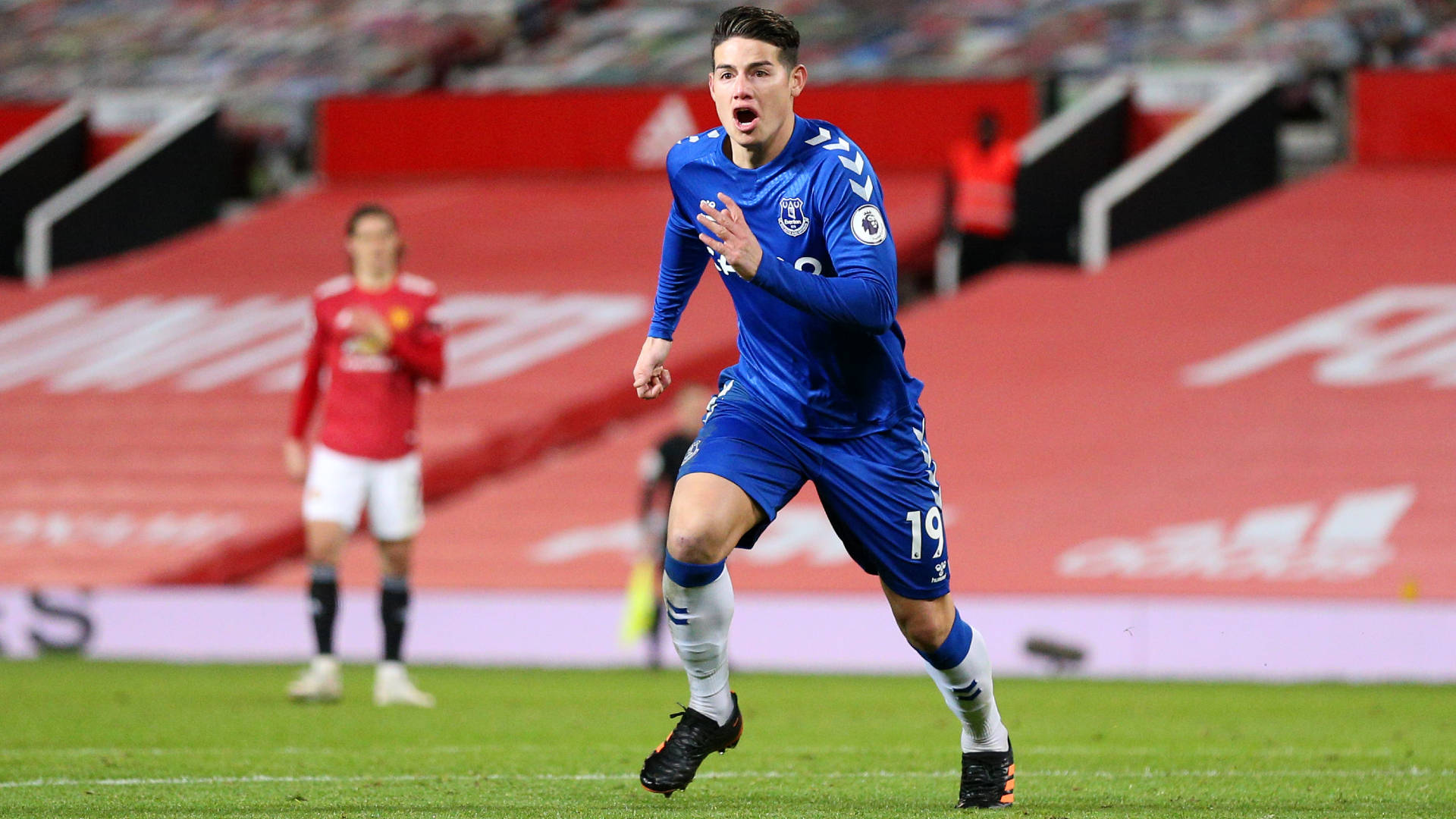 James Rodriguez 桌布 壁紙 — 一名身穿藍色球衣的足球運動員在體育場燈光下，在充滿活力的綠色球場上熱情慶祝。