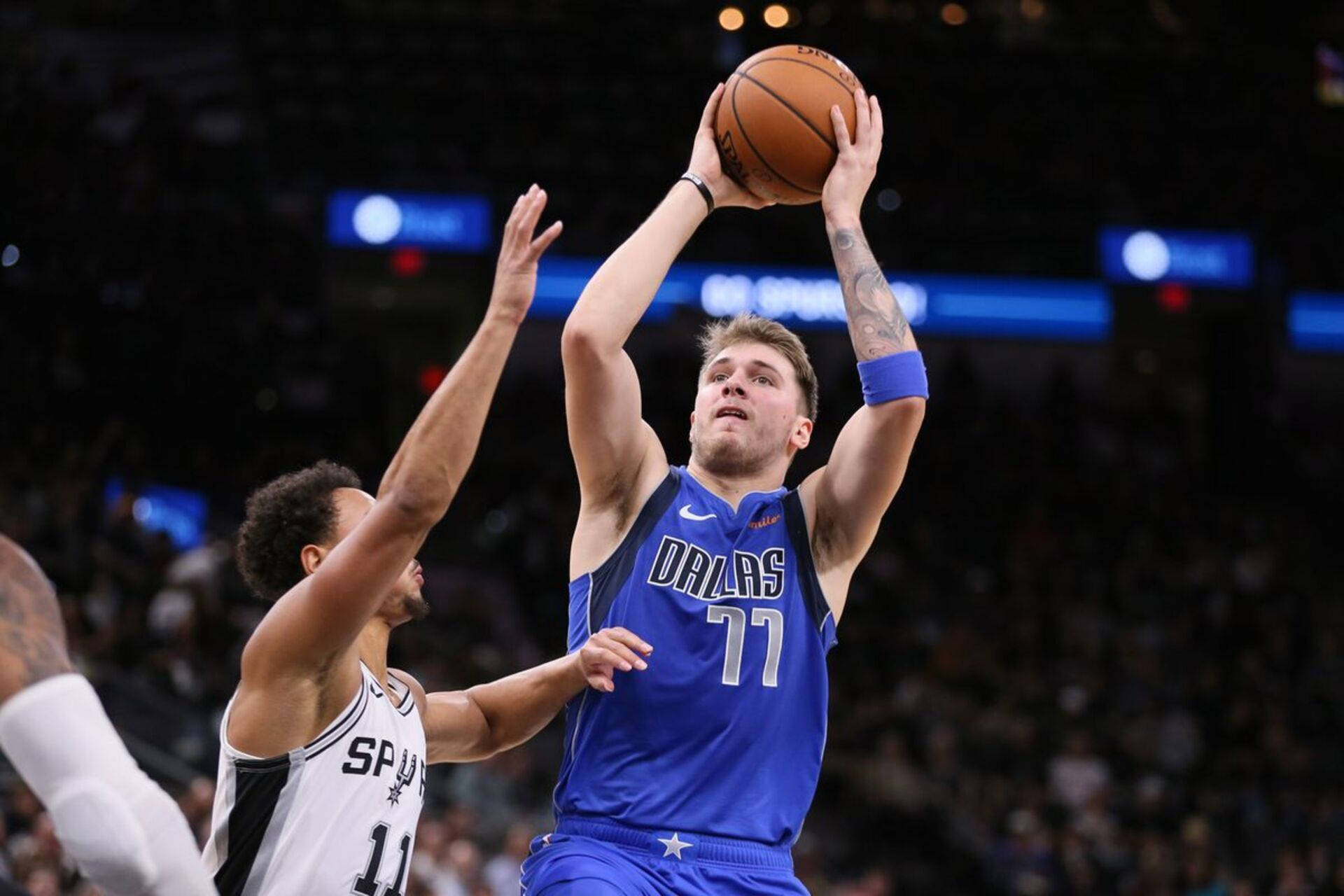 Luka 桌布 壁紙 — 一名身穿藍色球衣的達拉斯獨行俠球員投籃，而一名馬刺防守球員伸手封阻。