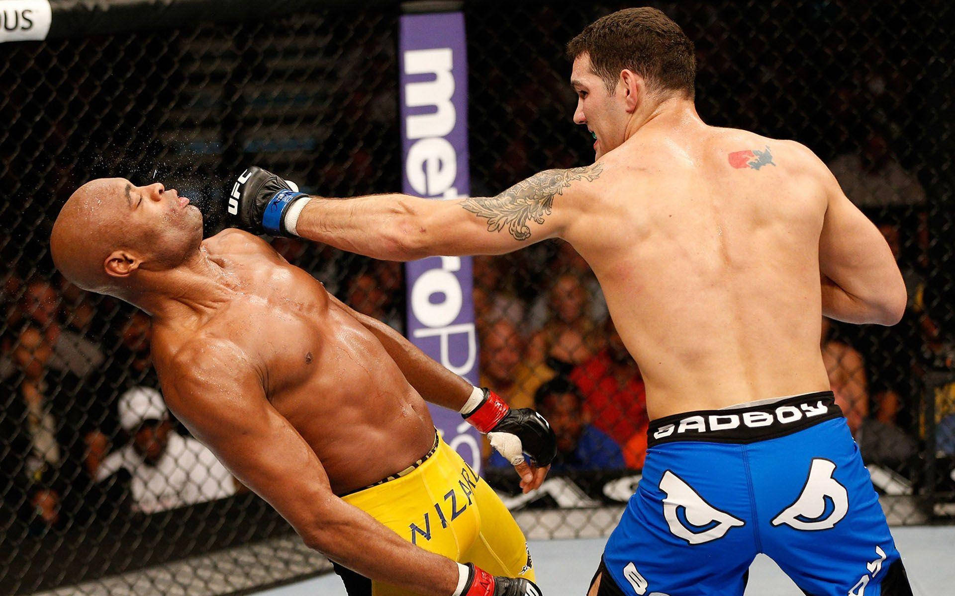Punch 桌布 壁紙 — 一名身穿藍色短褲的拳手在UFC八角籠內向身穿黃色短褲的對手打出強力一拳。