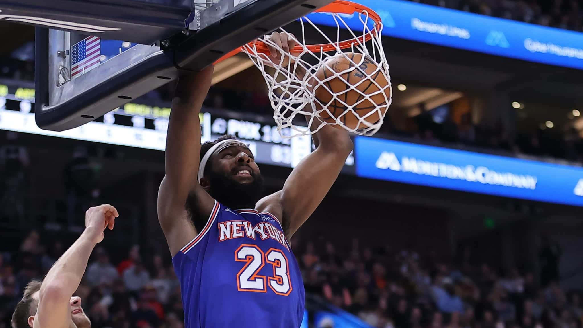 NBA 桌布 壁紙 — 一名身穿藍色紐約球衣的籃球運動員在明亮的場館燈光下，於比賽中專注地灌籃。