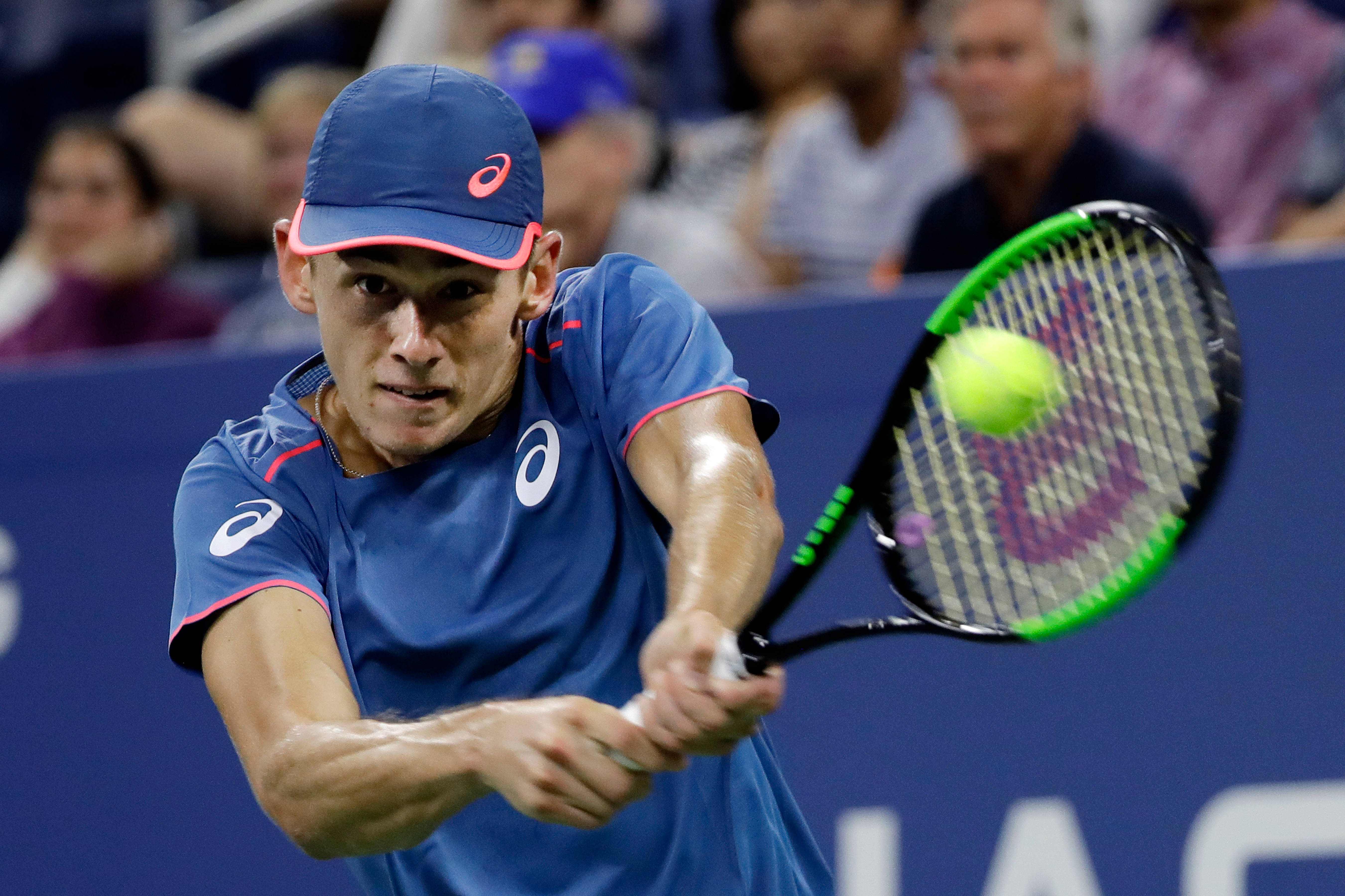 Tennis 桌布 壁紙 — 一名身穿藍色裝備的男性網球選手在體育場燈光下進行激烈比賽時，揮拍擊向一顆明亮的黃色球。