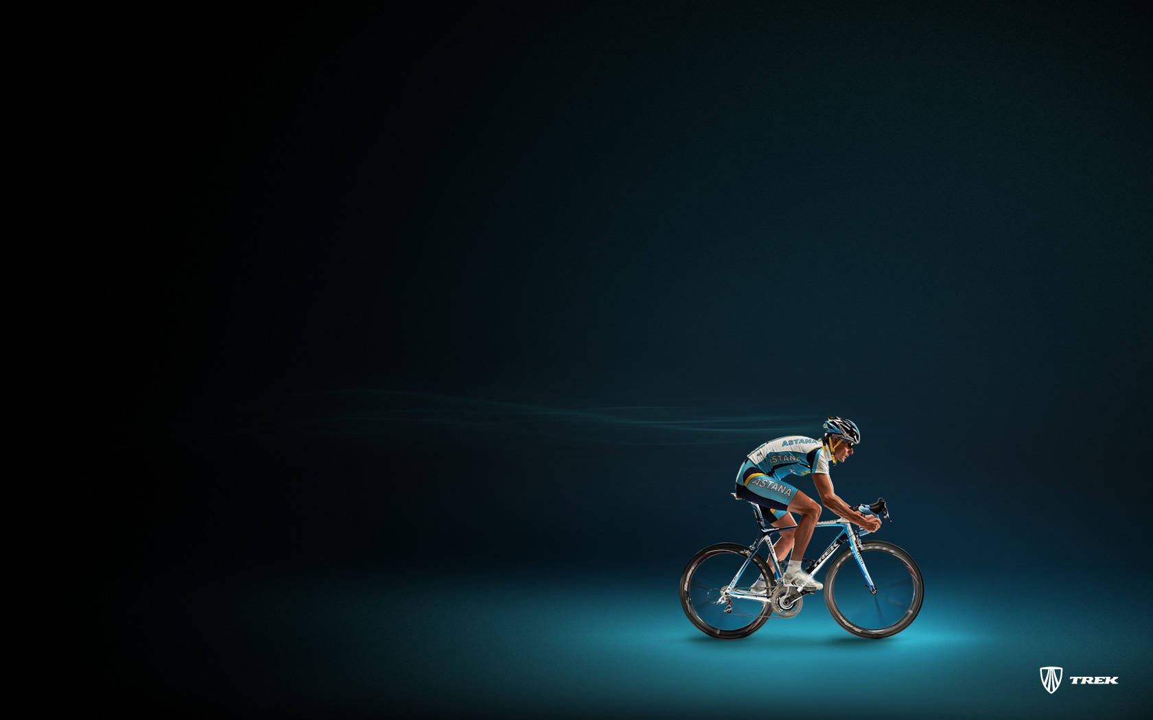 Cool Bike 桌布 壁紙 — 一名身穿藍色裝備的自行車手在深藍綠色工作室背景前，於戲劇性聚光燈下在時尚自行車上激烈踩踏。