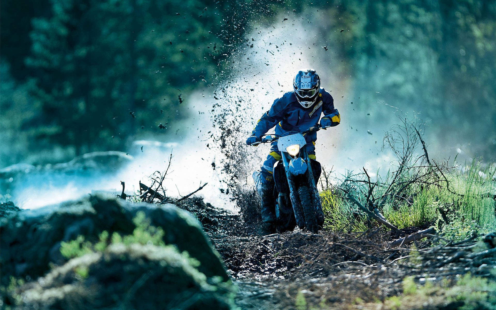 運動 桌布 壁紙 — 一名身穿藍色裝備的越野摩托車手在森林地區的泥濘地形上奔馳，激起泥漿。