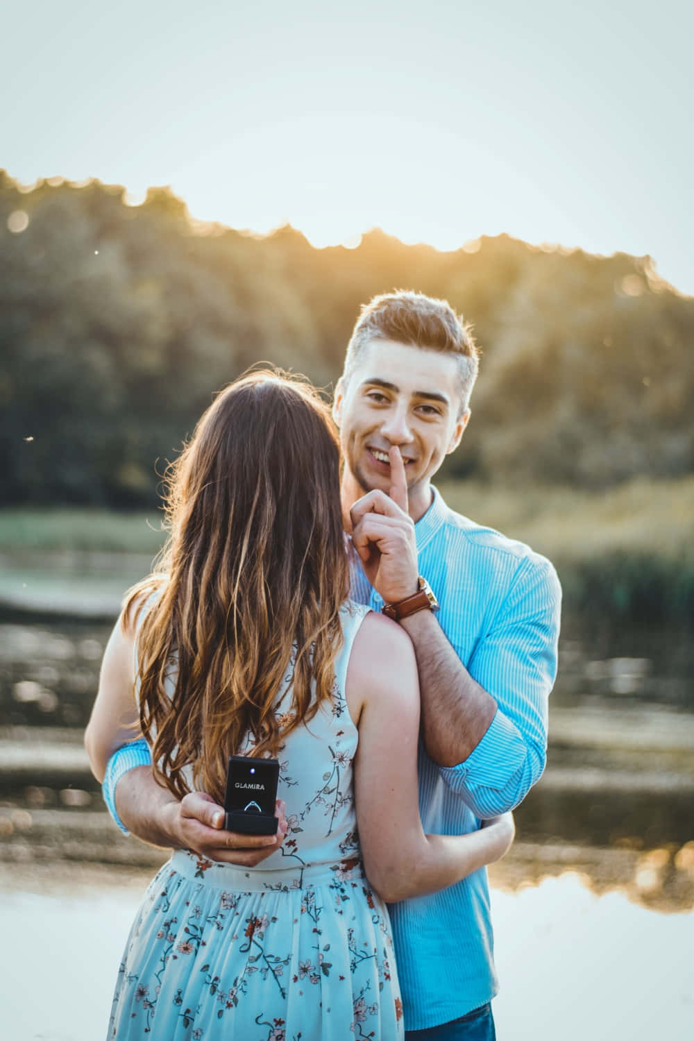 Proposal 桌布 壁紙 — 一名身穿藍色襯衫的男子，在金色時刻的陽光湖畔，向一位身穿碎花裙的女子低語秘密。
