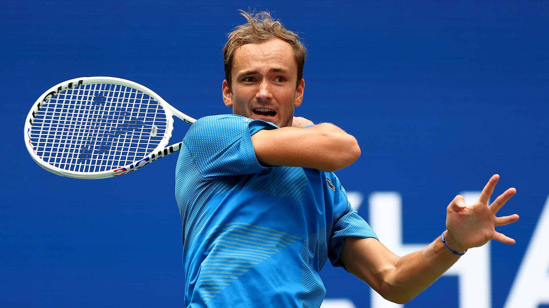Tennis 桌布 壁紙 — 一名身穿藍色襯衫的男性網球運動員在純藍色背景下專注地揮動球拍。
