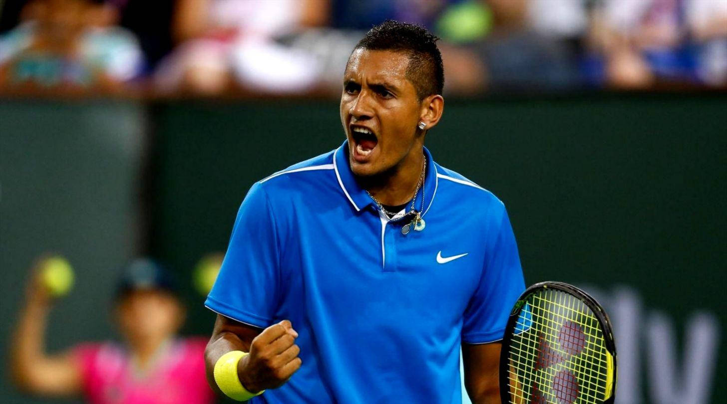 Kyrgios 桌布 壁紙 — 一名身穿藍色襯衫的男網球運動員在球場上緊握拳頭、張開嘴巴熱情慶祝。