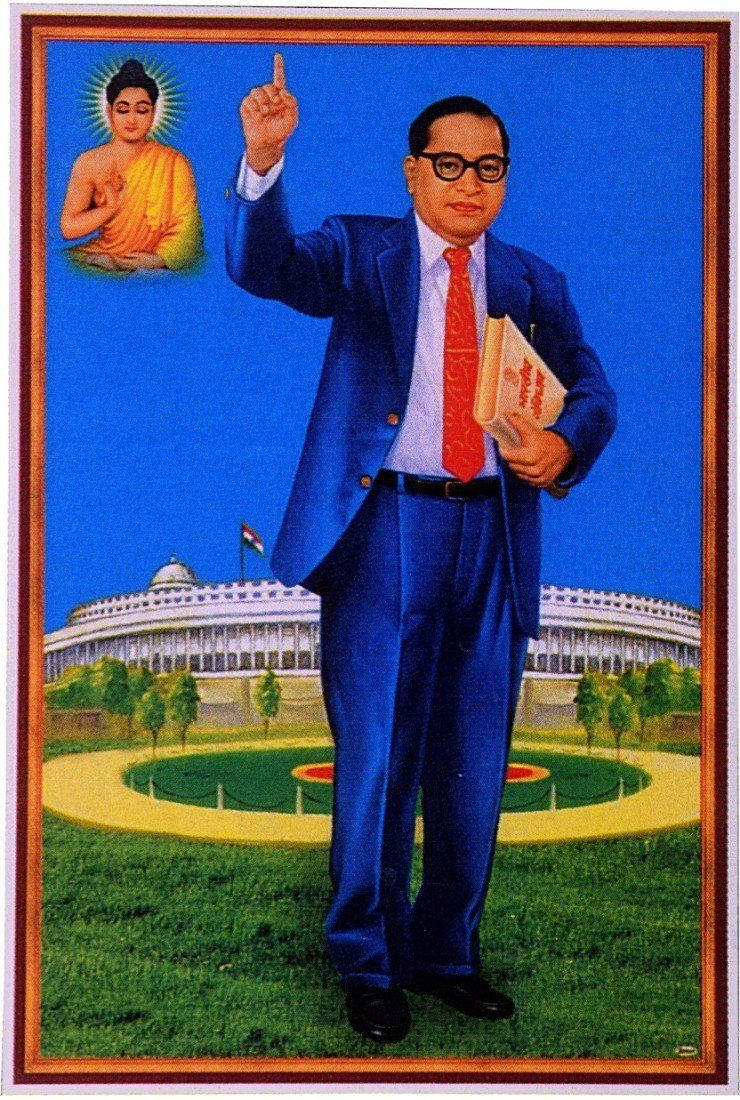 Dr Babasaheb Ambedkar 桌布 壁紙 — 一名身穿藍色西裝和紅色領帶的男子站在草地上，手持書籍向上指，身後有佛像和圓頂建築。