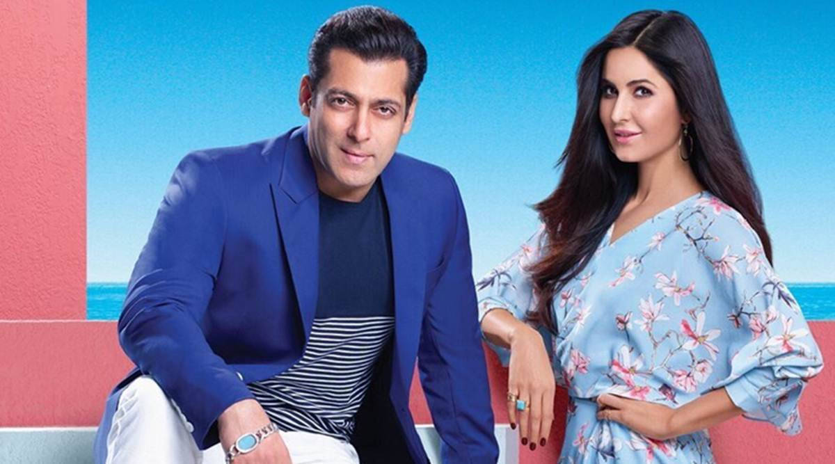 salman khan HD 桌布 壁紙 — 一名身穿藍色西裝外套的男子和一名身穿花卉連衣裙的女子在充滿活力的粉紅色和藍色背景前自信地擺姿勢，背景是海景。