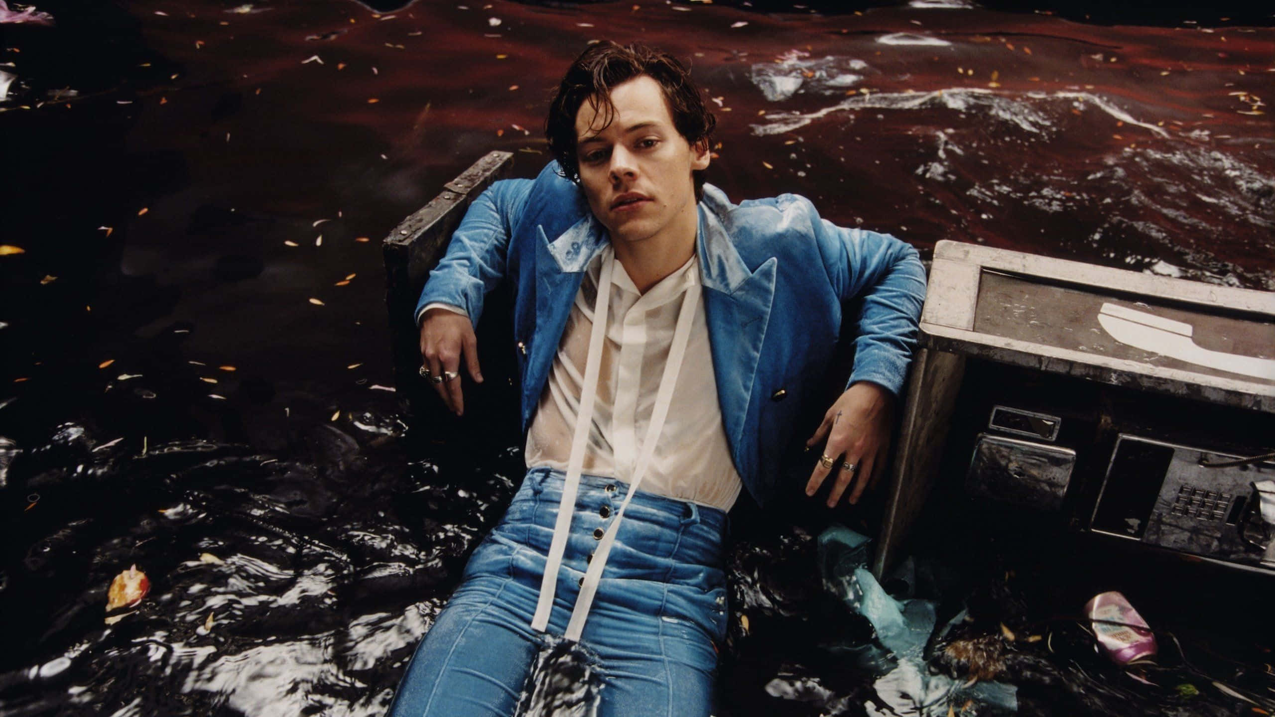 Harry Styles Laptop 桌布 壁紙 — 一名身穿藍色西裝的男子在黑暗的水中漂浮，旁邊是一部浸沒的電視機，火花四濺。