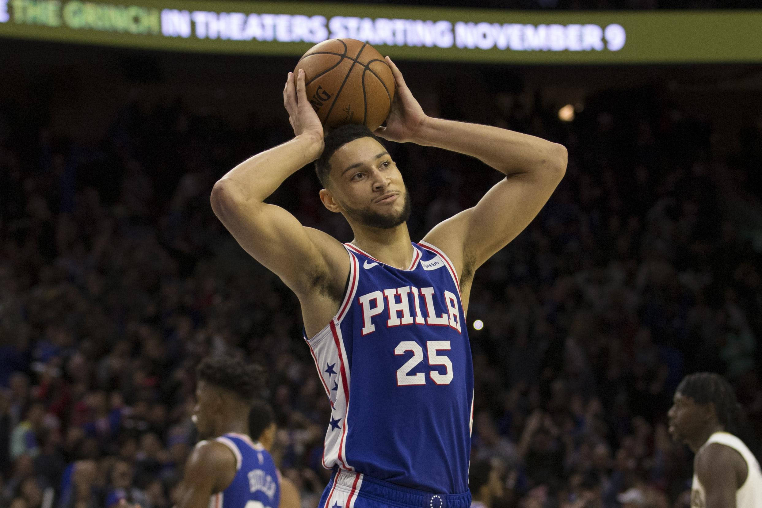 Ben Simmons 桌布 壁紙 — 一名身穿藍色費城球衣的籃球運動員在場館燈光下準備投籃，身後是模糊的人群。
