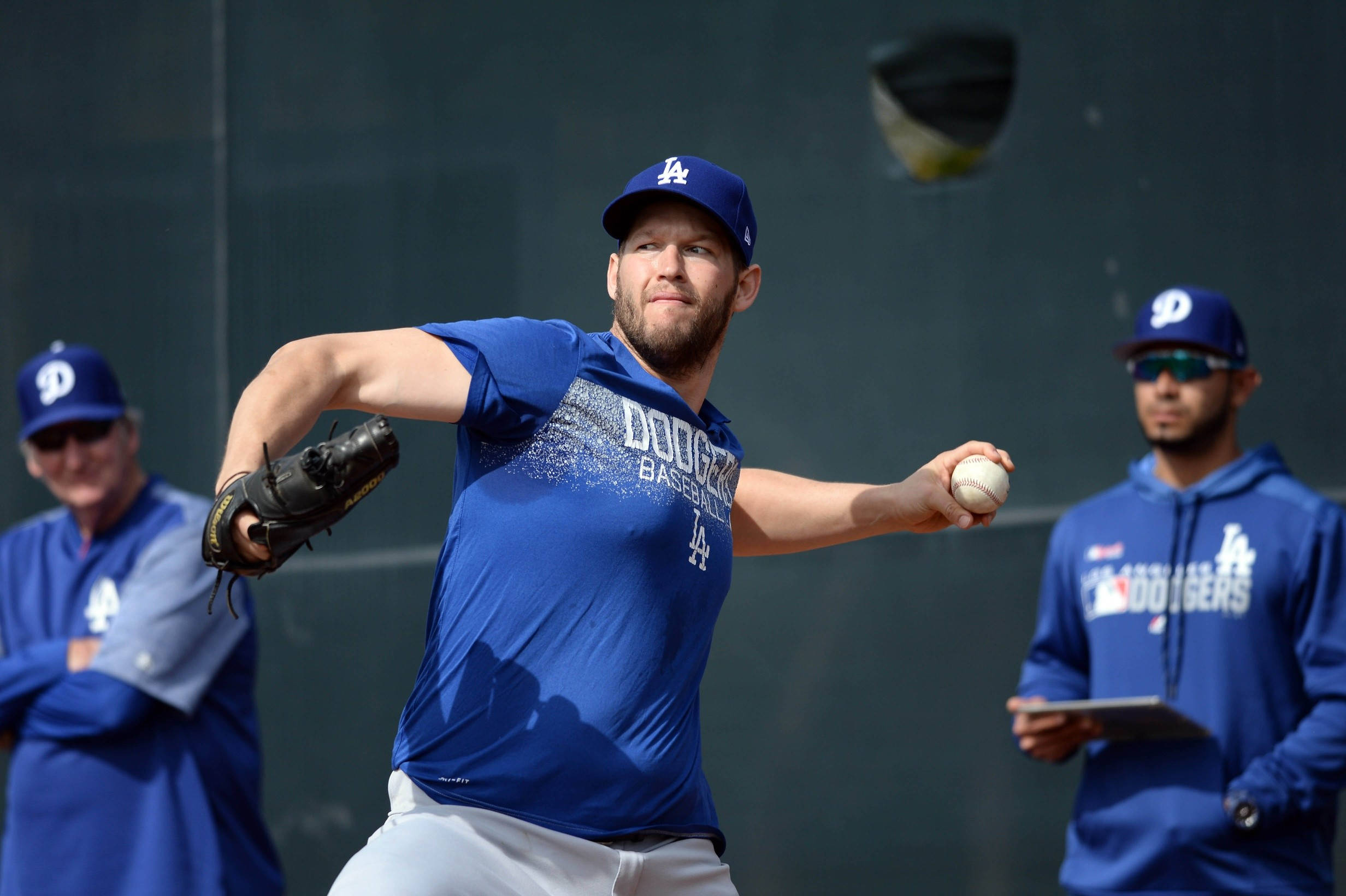 La Dodgers 桌布 壁紙 — 一名身穿藍色道奇隊球衣的棒球投手，在深綠色牆壁前投球，棒球正在運動中。