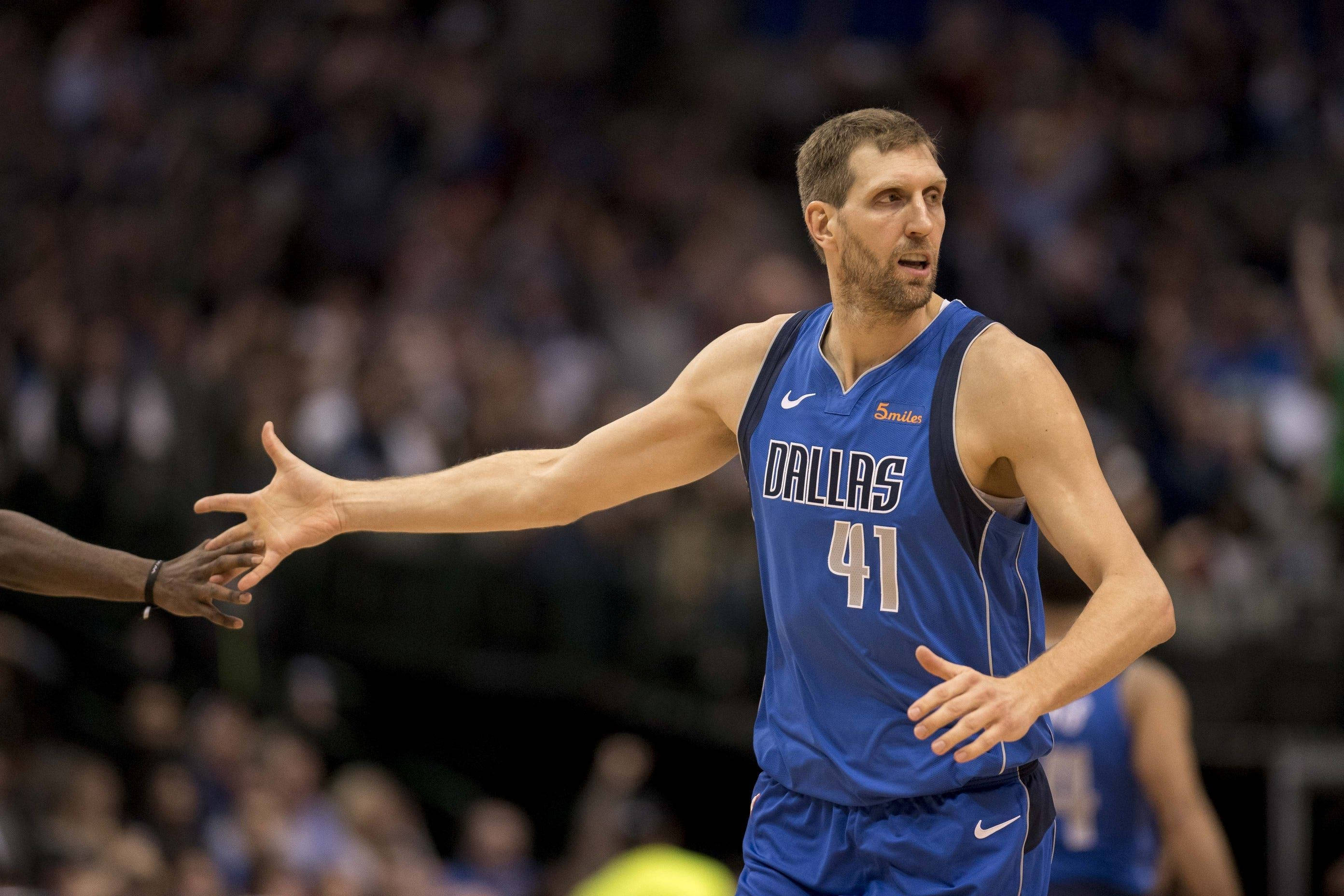 Dirk Nowitzki 桌布 壁紙 — 一名身穿藍色達拉斯球衣、號碼41的籃球運動員在比賽中伸出手，背景有觀眾觀看。
