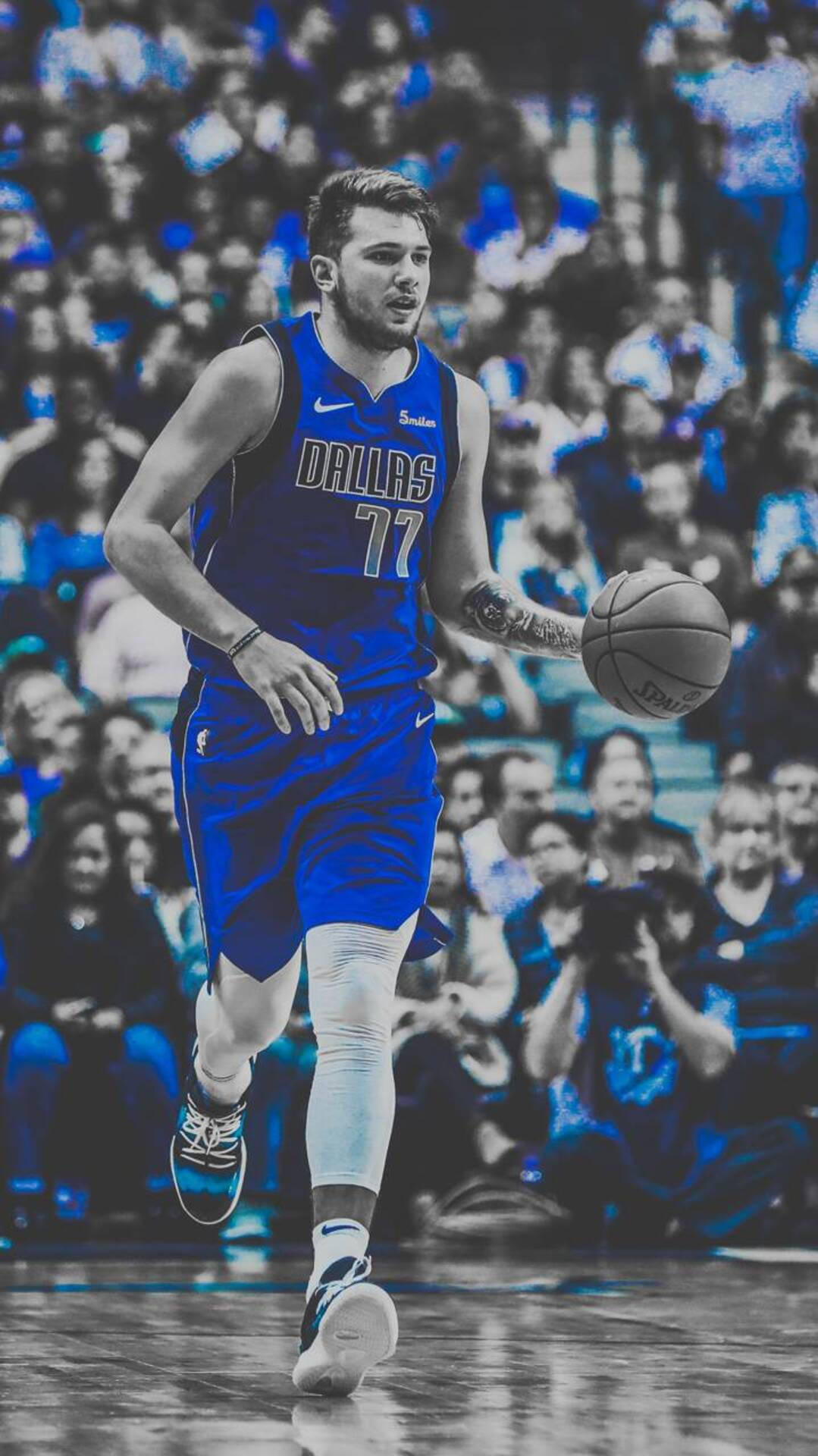 Luka 桌布 壁紙 — 一名身穿藍色達拉斯球衣的籃球運動員在比賽中運球，背景是模糊的人群。