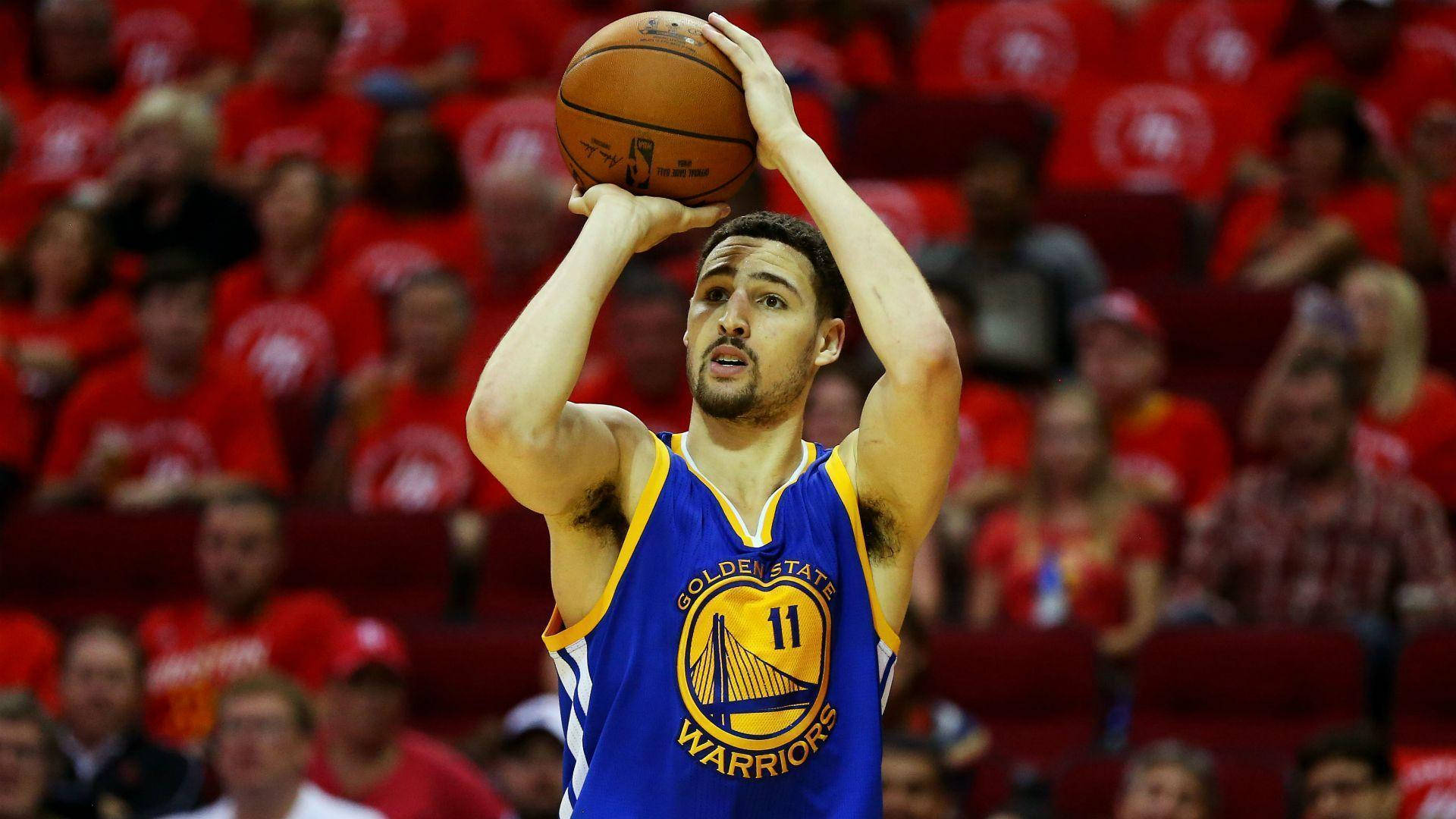 Thompson 桌布 壁紙 — 一名身穿藍色金州勇士隊球衣的籃球運動員，在擠滿觀眾的場館中，專注地準備投籃。