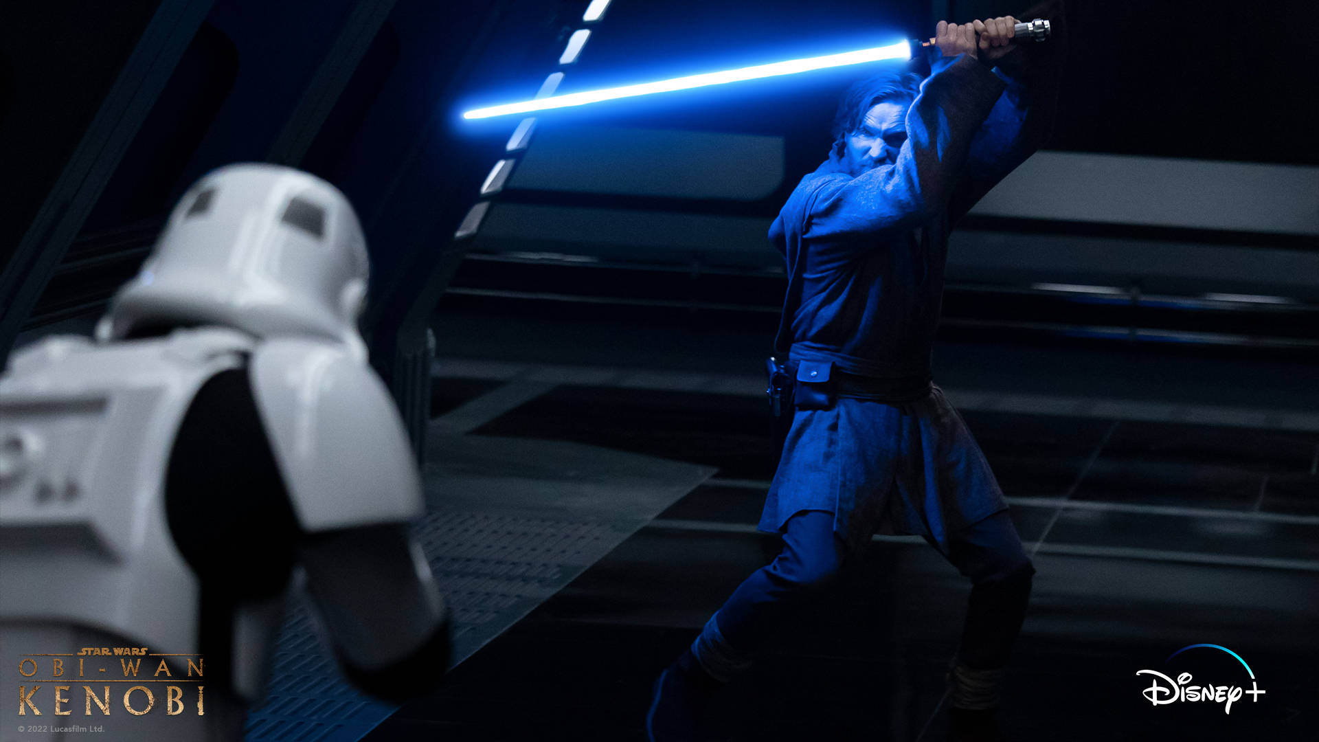 Kenobi 桌布 壁紙 — 一名身穿藍色長袍的絕地武士在昏暗的未來風格走廊中，用發光的藍色光劍與暴風兵決鬥。