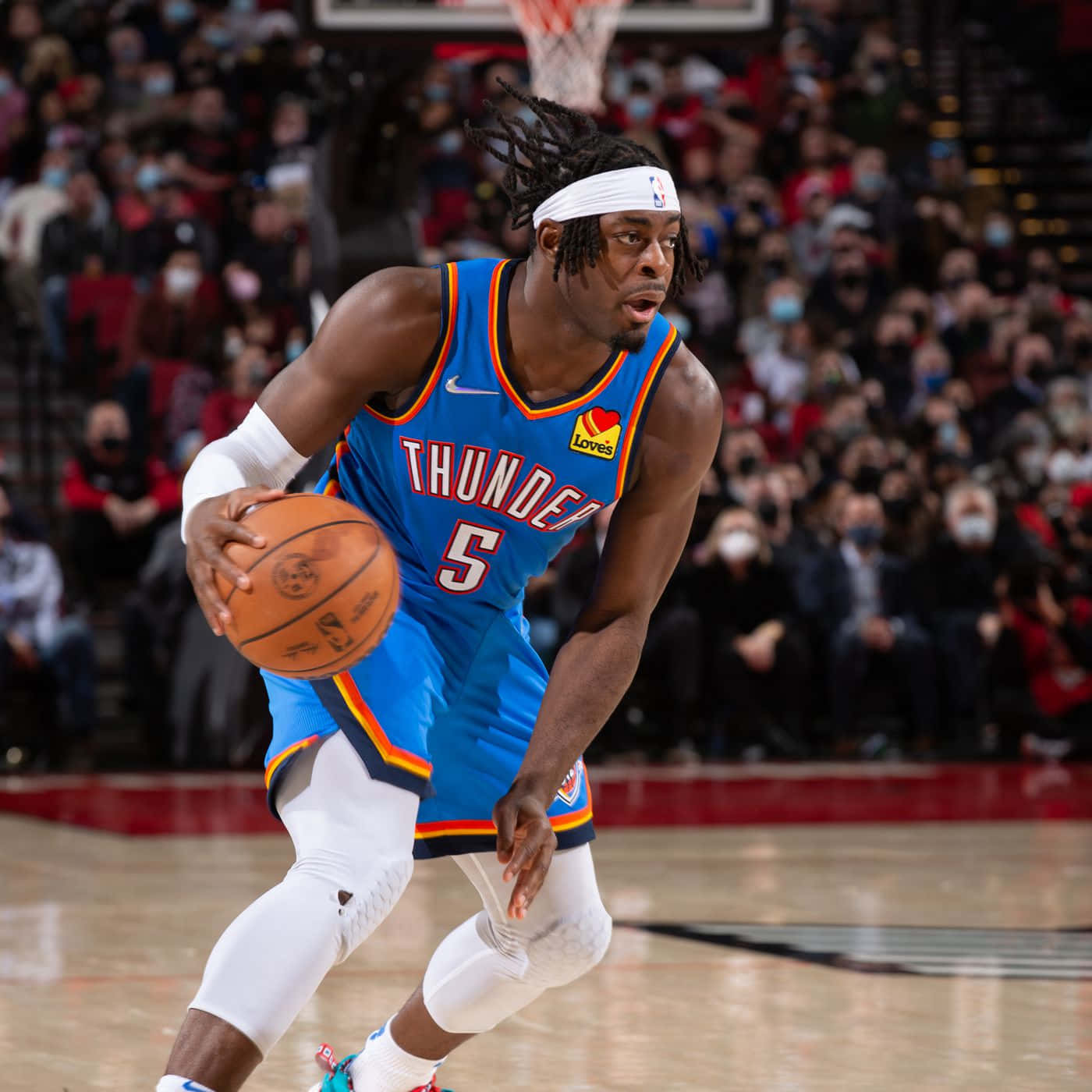 NBA 桌布 壁紙 — 一名身穿藍色雷霆球衣的籃球運動員在比賽中激烈運球，背景是擠滿戴著口罩的人群。