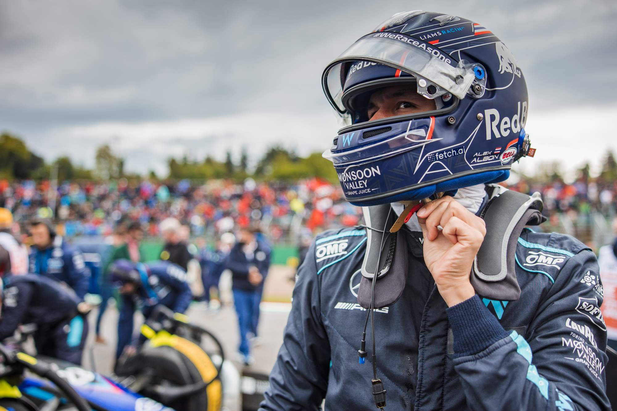 Racing 桌布 壁紙 — 一名身穿藍色頭盔和賽車服的賽車手在賽車活動中被人群包圍，調整他的裝備。