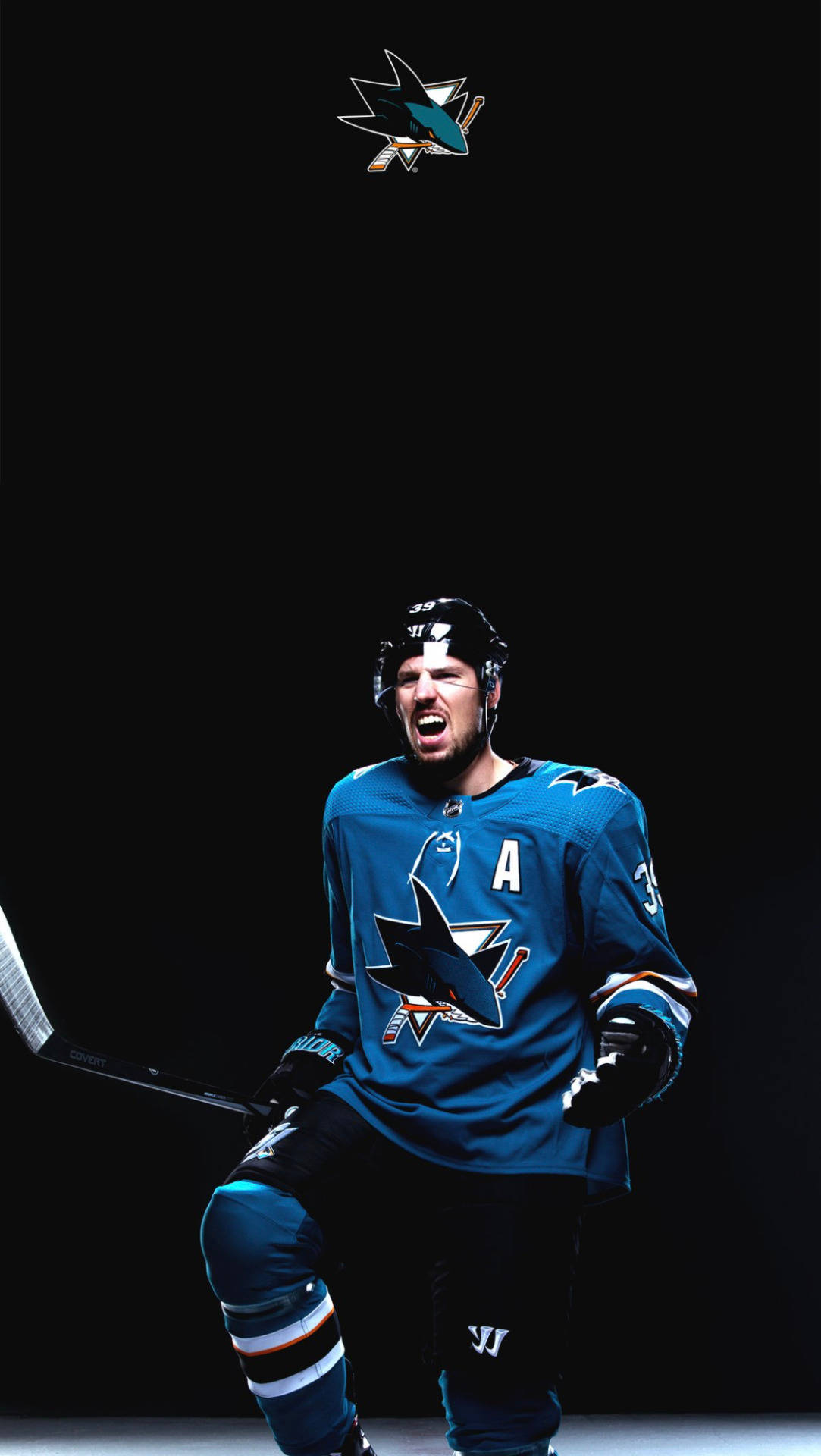 hockey 桌布 壁紙 — 一名身穿藍色鯊魚隊球衣的冰球運動員在黑色背景下激烈咆哮。